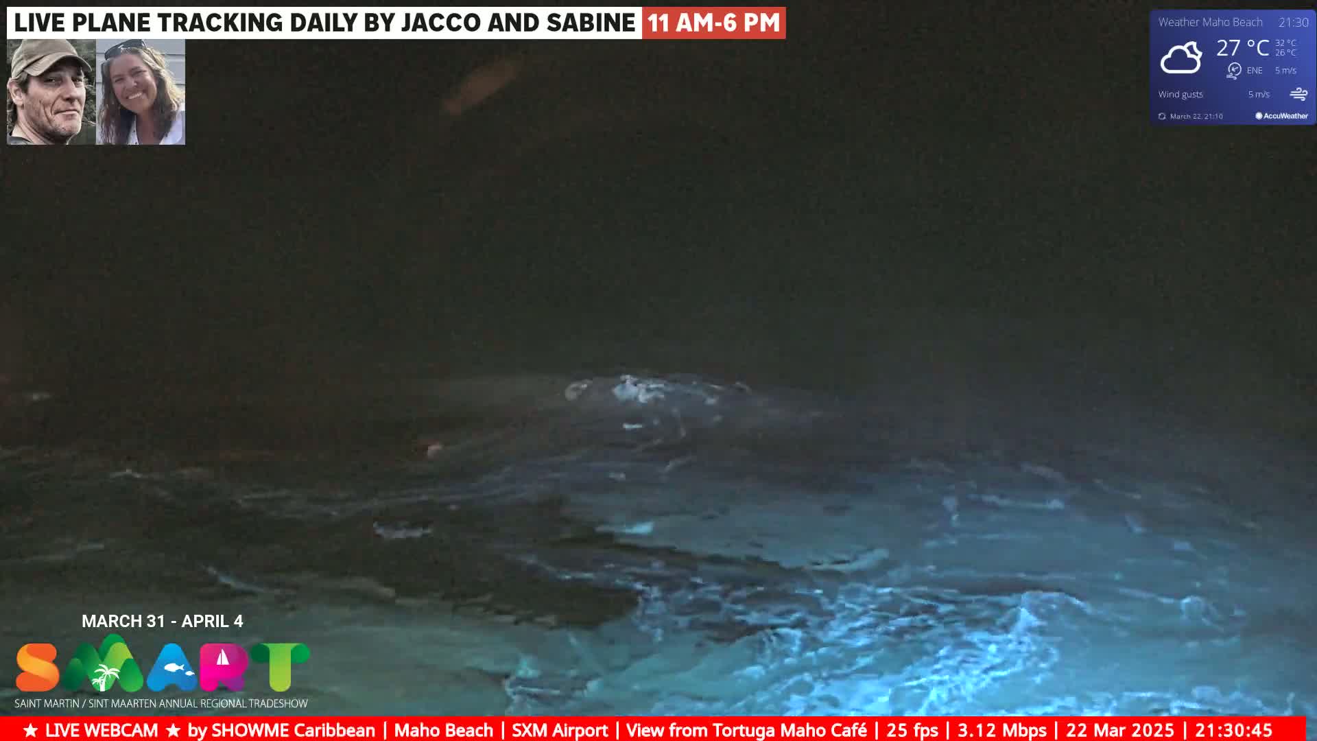 A nighttime view of bioluminescent ocean waves under partly cloudy skies.