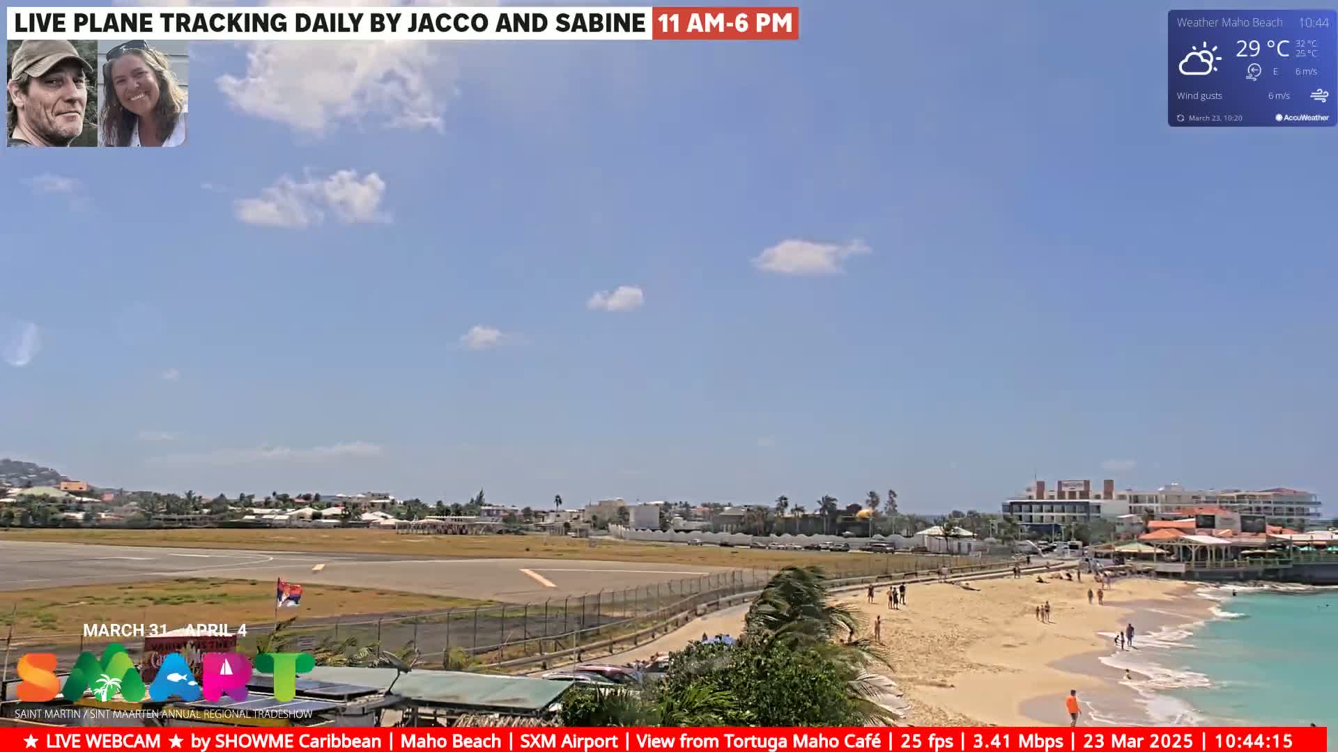 A sunny day shows an airport runway, beach with people, and buildings under a mostly clear sky.