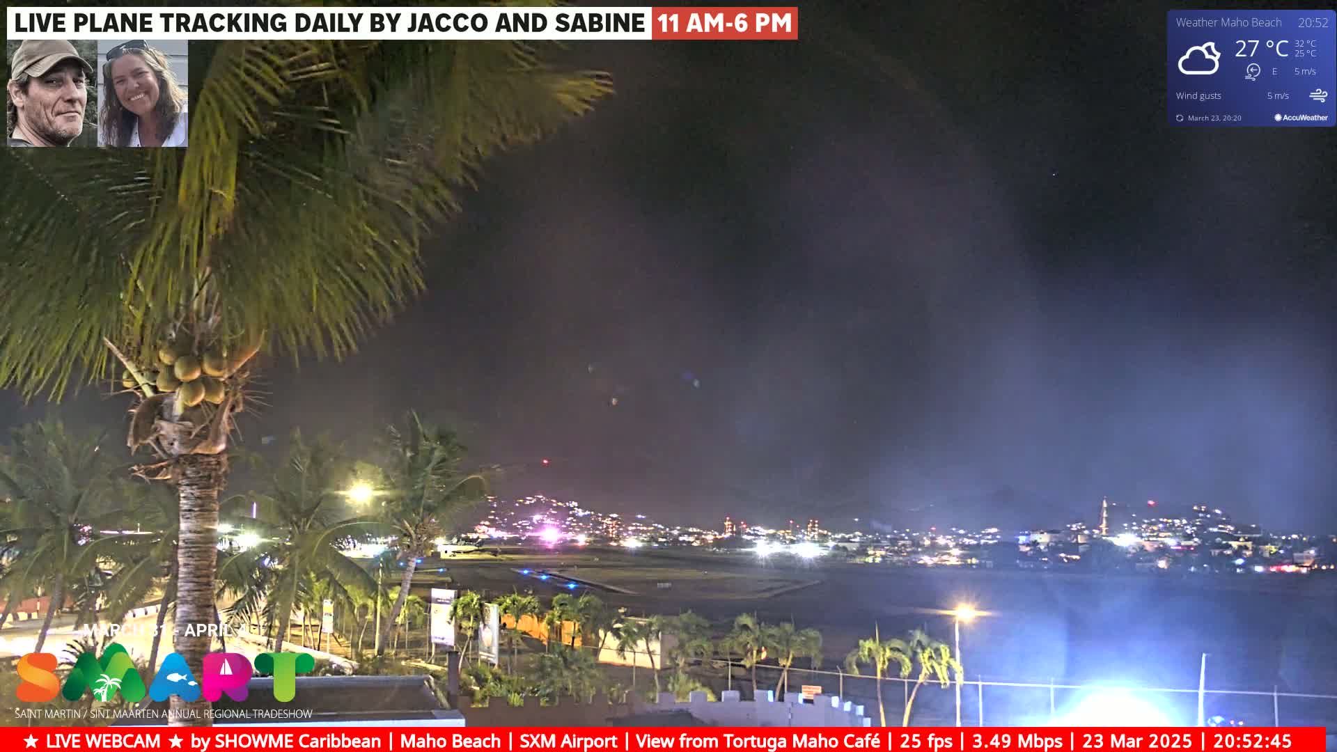 A nighttime view of an airport runway and surrounding palm trees, under a partly cloudy sky.