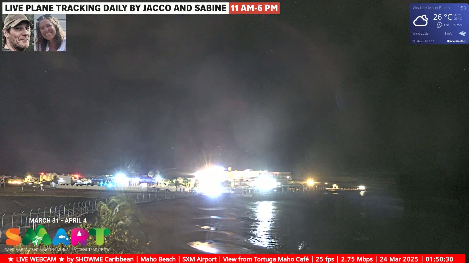 A nighttime view of a beach with dimly lit buildings and a calm ocean under a dark sky.