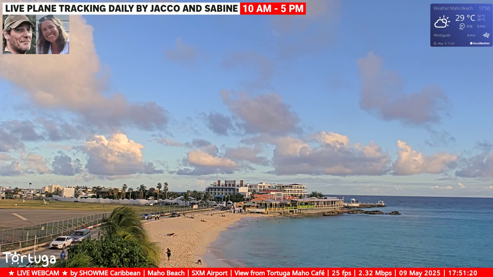 A partly cloudy sky over a beach with turquoise water, buildings, and a runway.