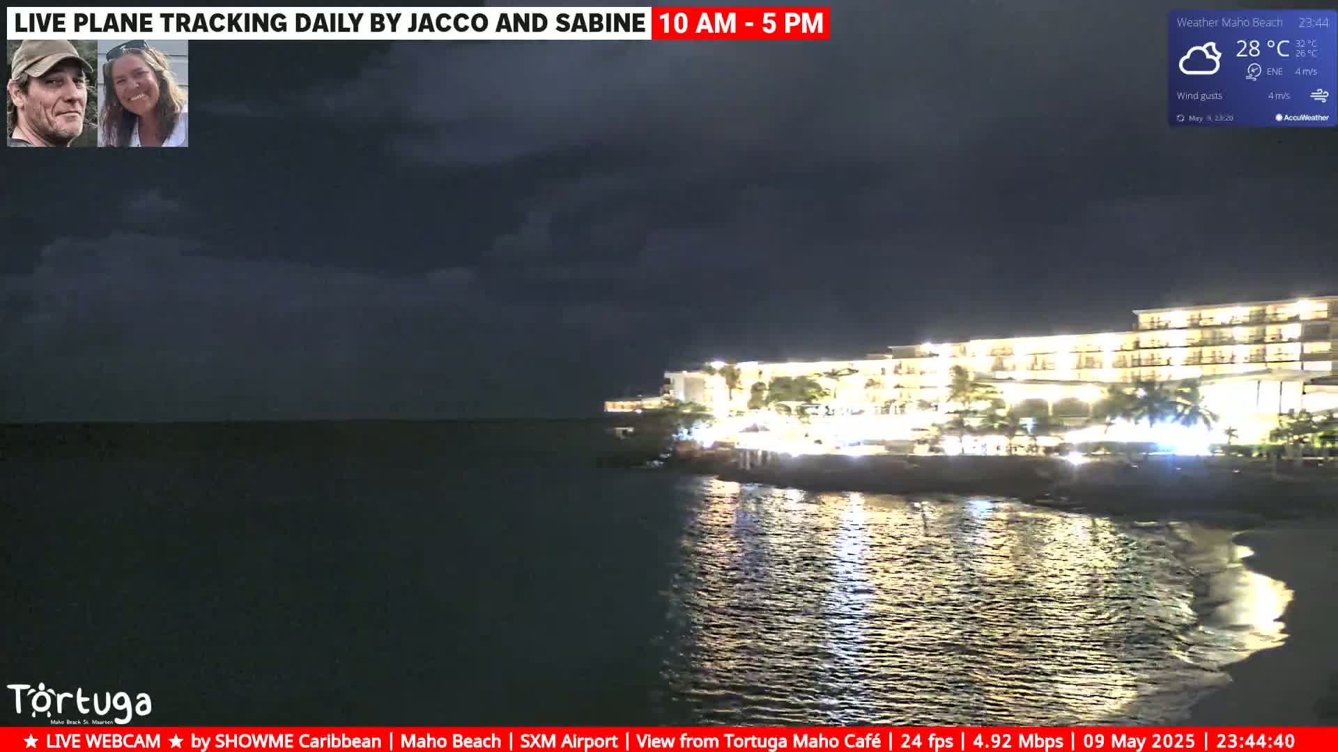 A brightly lit resort is seen across a dark body of water at night under cloudy skies.