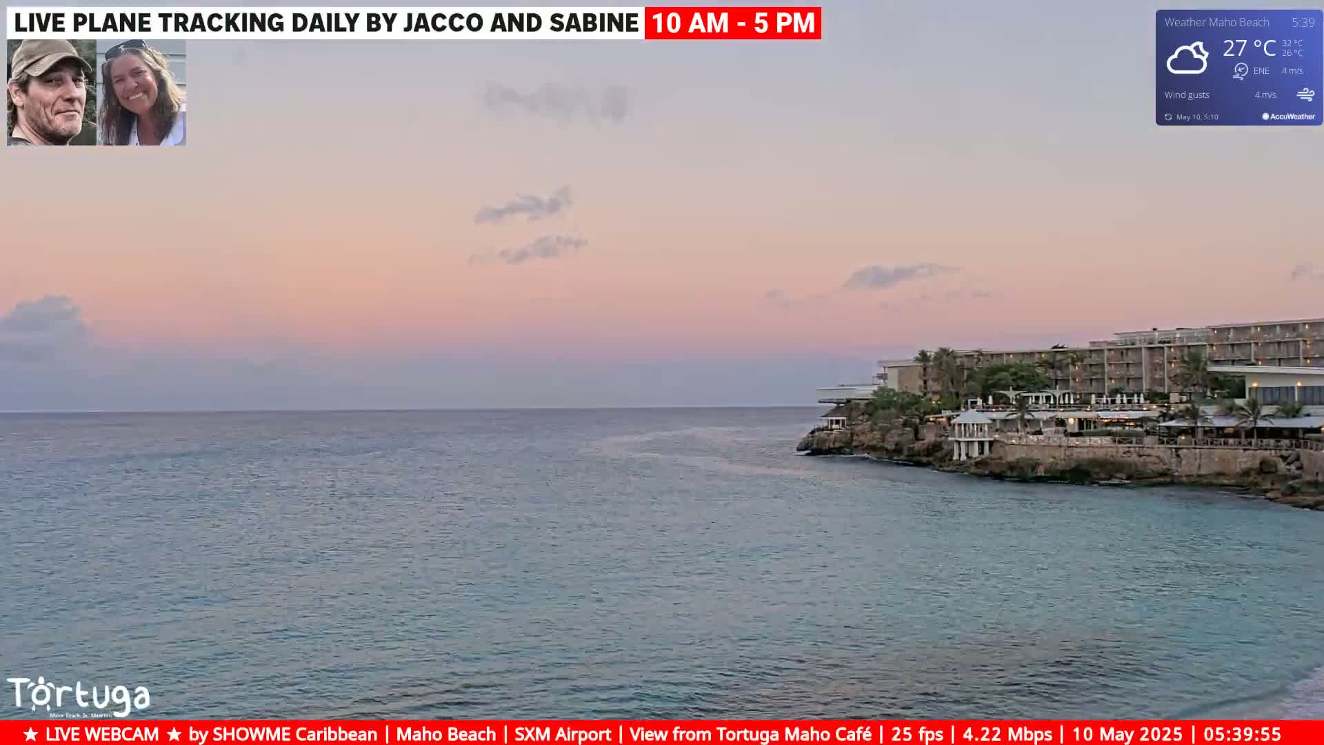 A calm ocean with a pinkish sunset sky over a coastal resort.