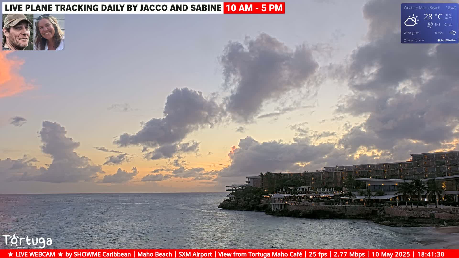 An ocean view at sunset shows a partially cloudy sky over a resort on a rocky coast.