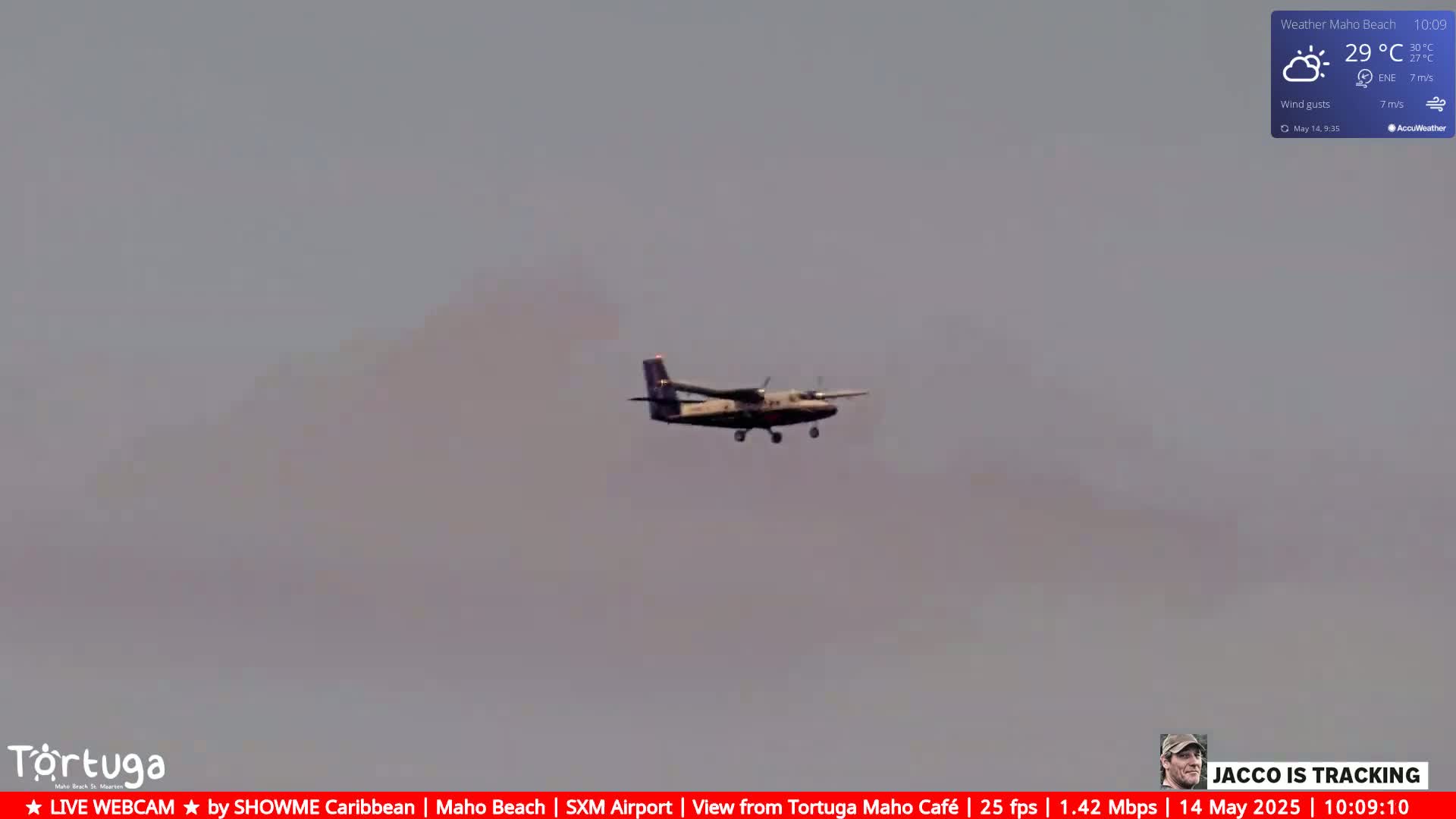 A small airplane flies in a hazy sky under partly sunny conditions.
