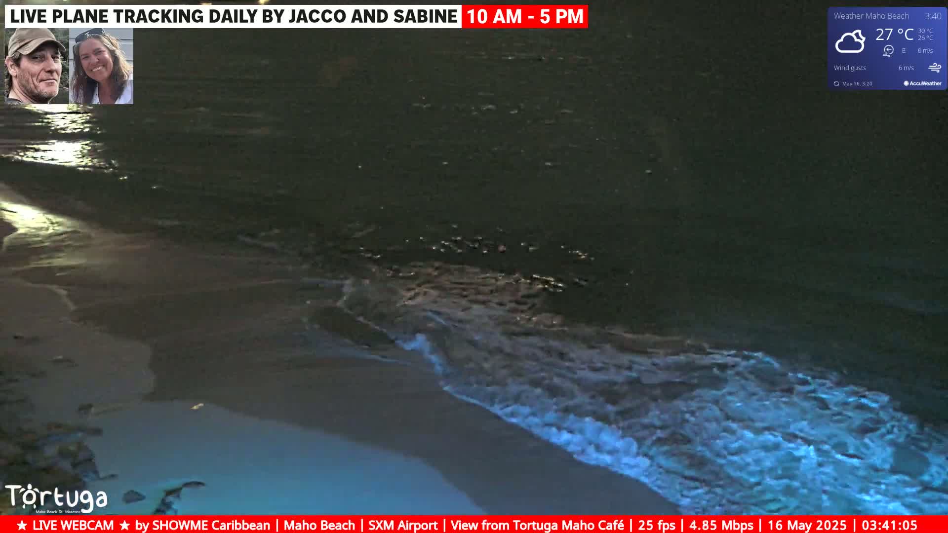 Dark, nighttime waves glowing faintly blue are lapping onto a sandy beach under cloudy skies.