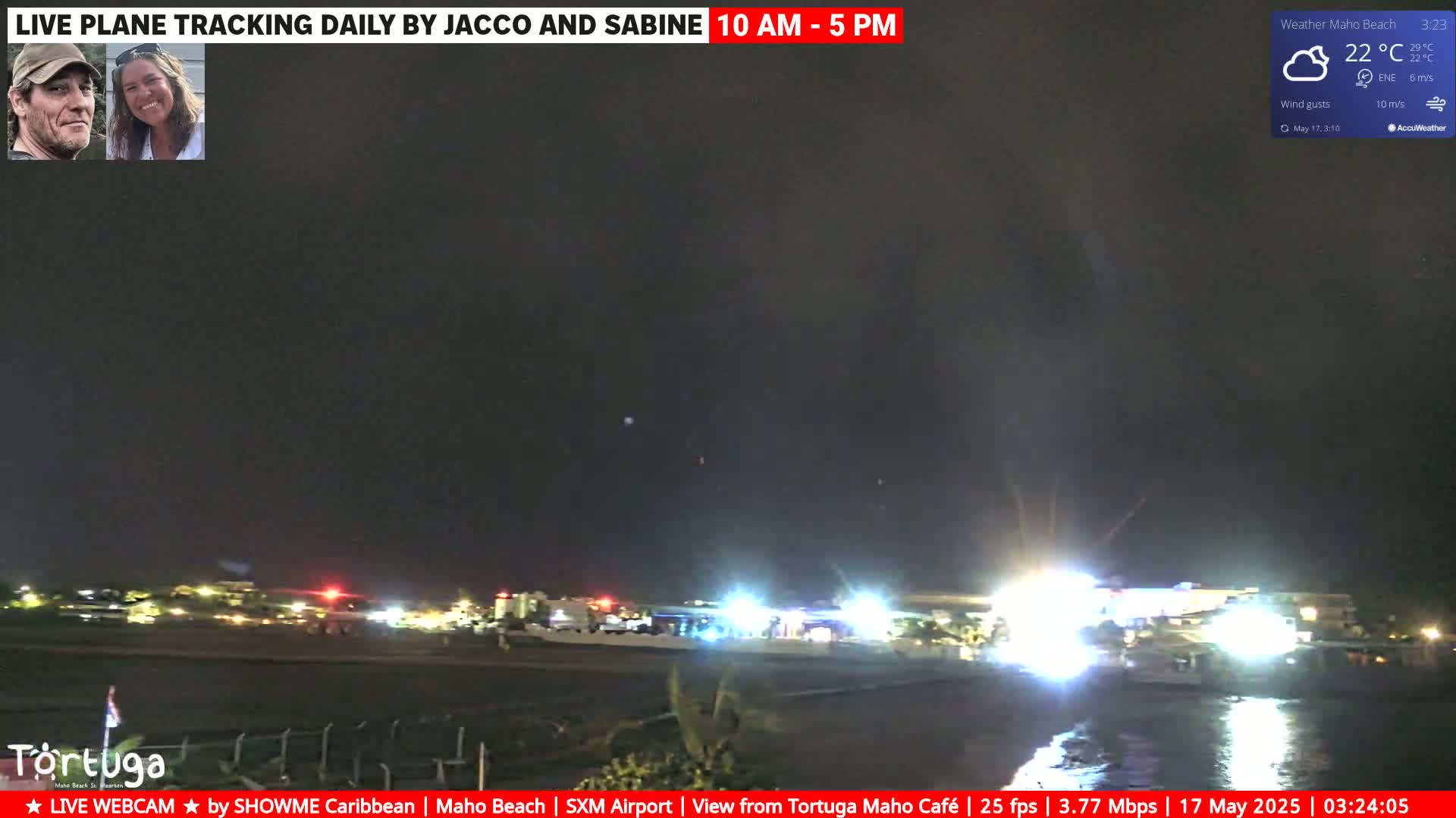 A nighttime view of a beach with lights from buildings and a partly cloudy sky, with a light wind.
