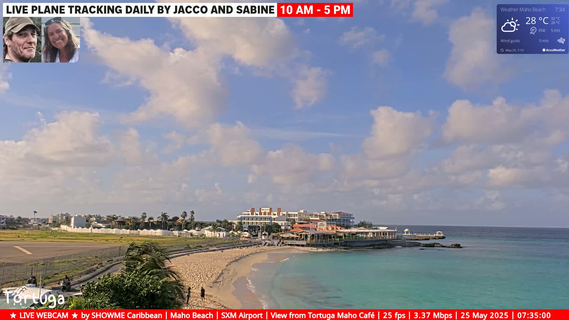 A partly cloudy sky over a beach with turquoise water, buildings, and a runway.