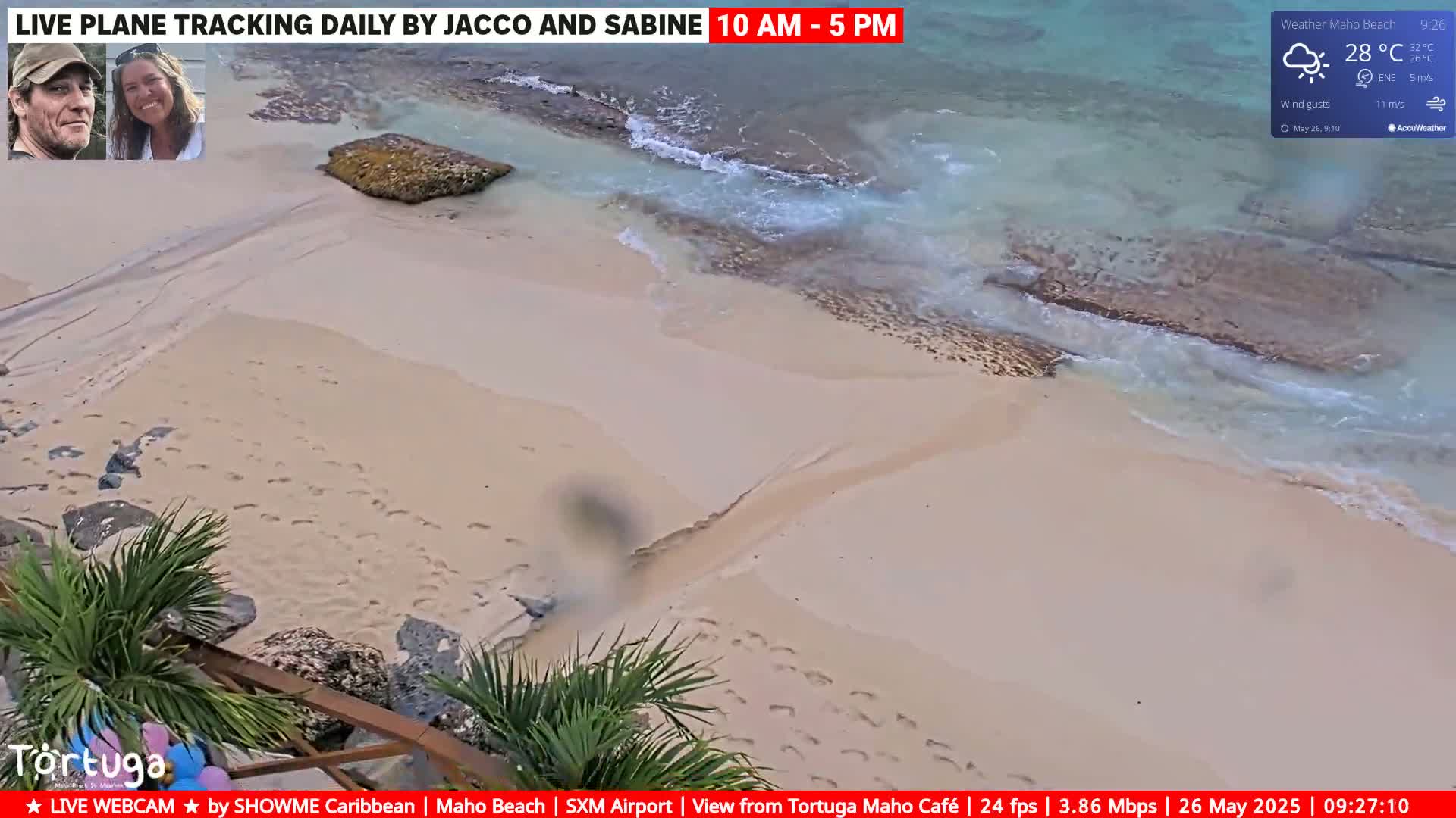 A mostly sunny beach scene shows light-colored sand, gentle waves, and a large rock near the water's edge, with a temperature of 28°C.
