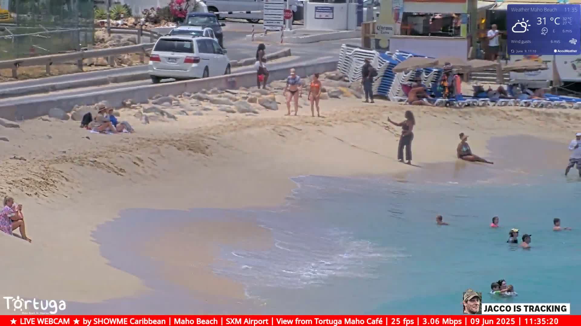 A sunny beach scene shows people relaxing on the sand and swimming in calm, turquoise water.