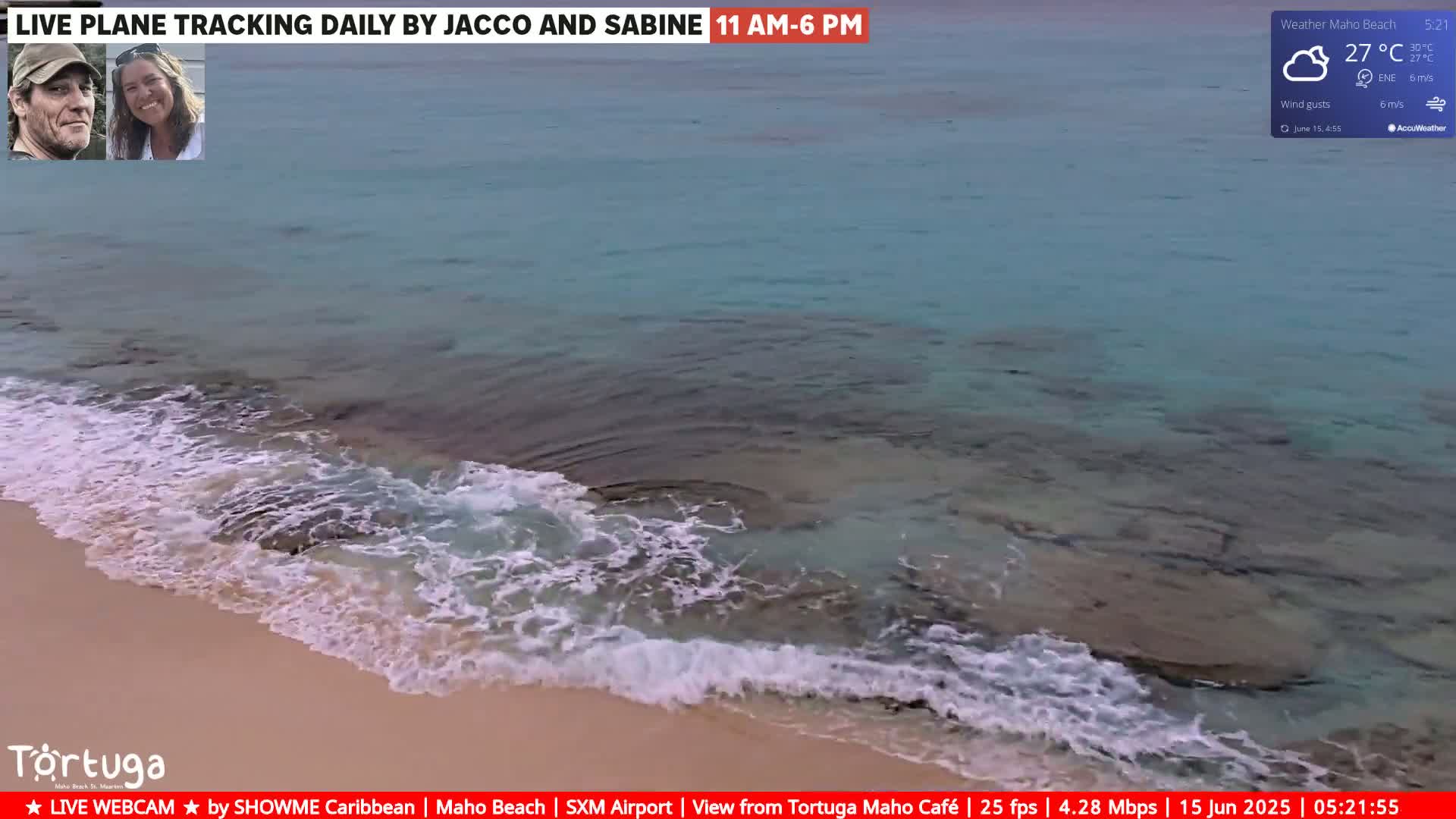 Gentle waves lap a sandy beach with clear, turquoise water under partly cloudy skies.