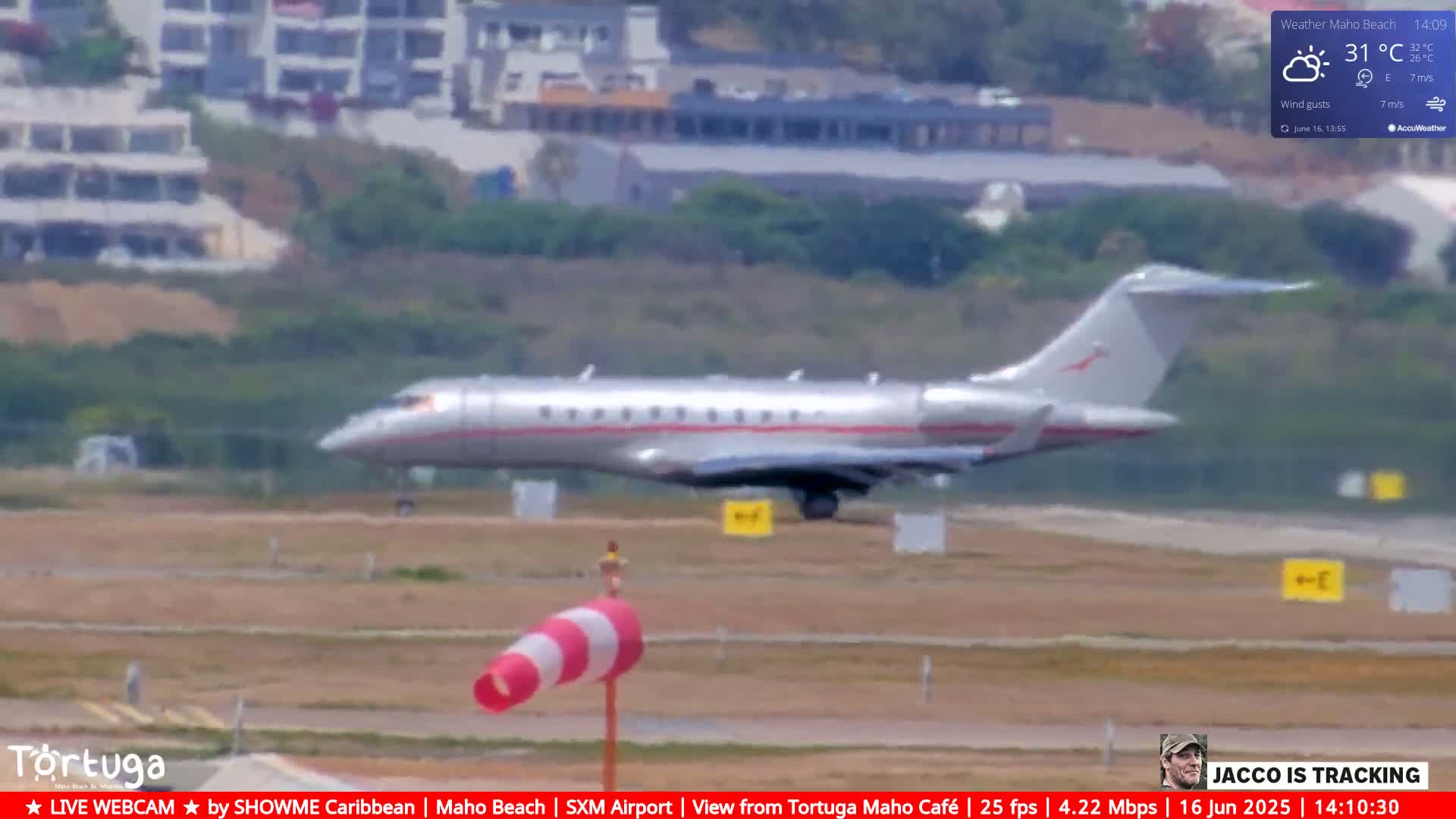 A silver private jet is landing on an airport runway on a partly sunny day.