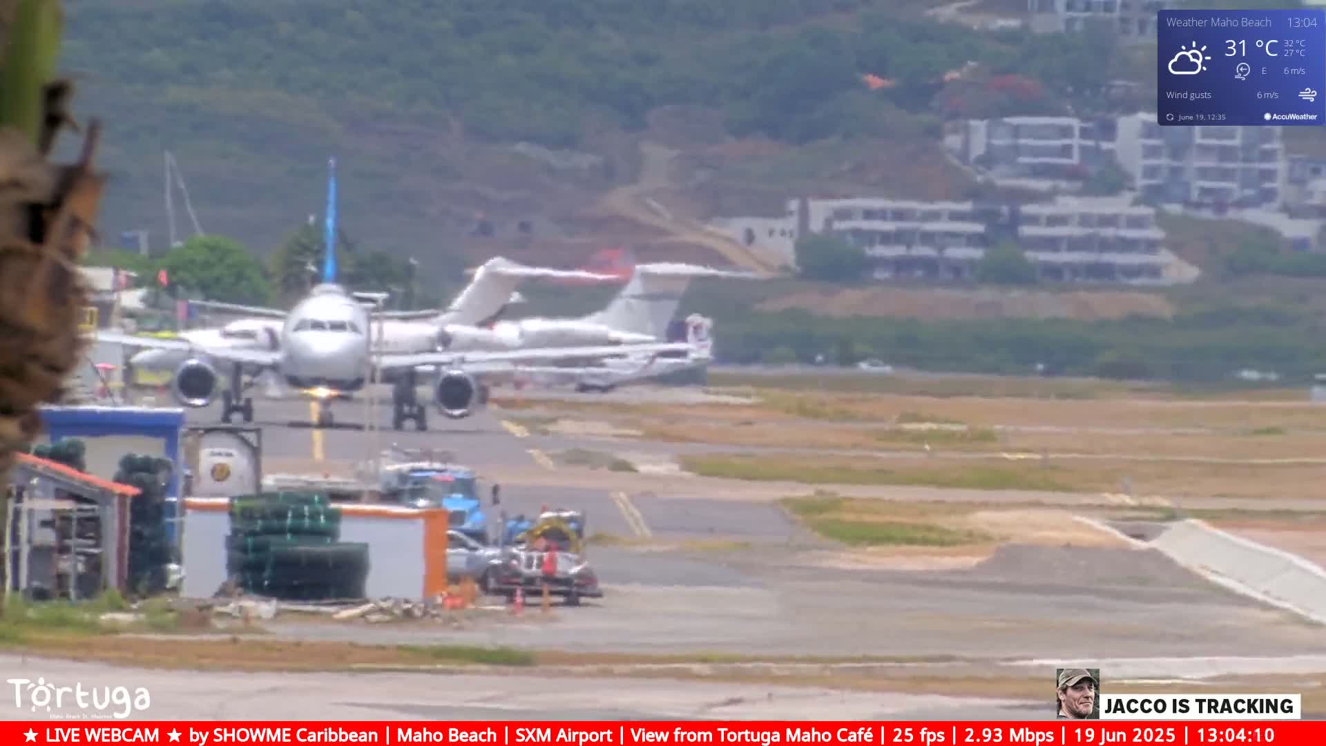 A large passenger airplane is landing on an airport runway next to a smaller private jet, under partly cloudy skies.