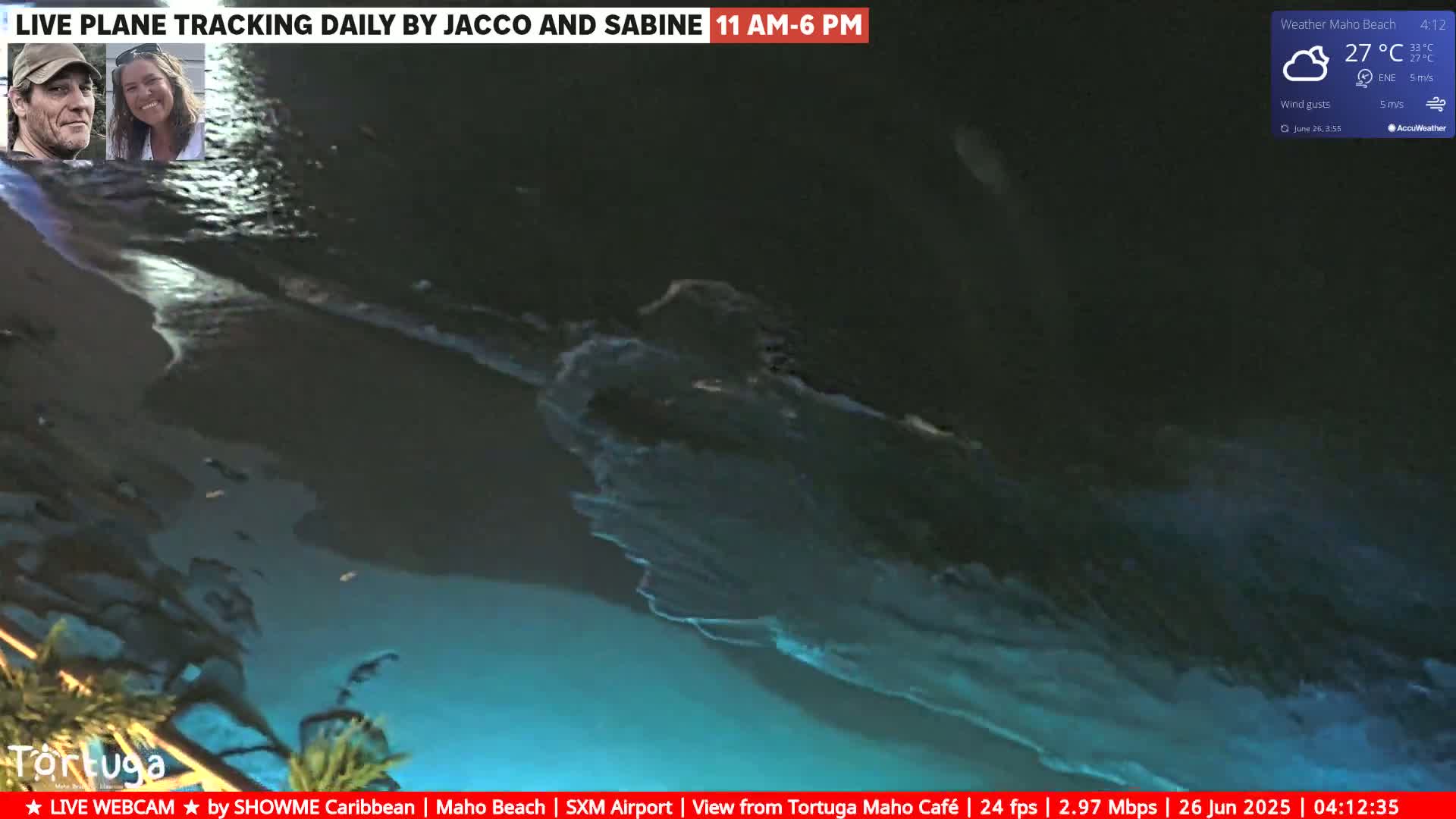 A nighttime beach scene shows dark water with lighter blue waves under a partly cloudy sky.