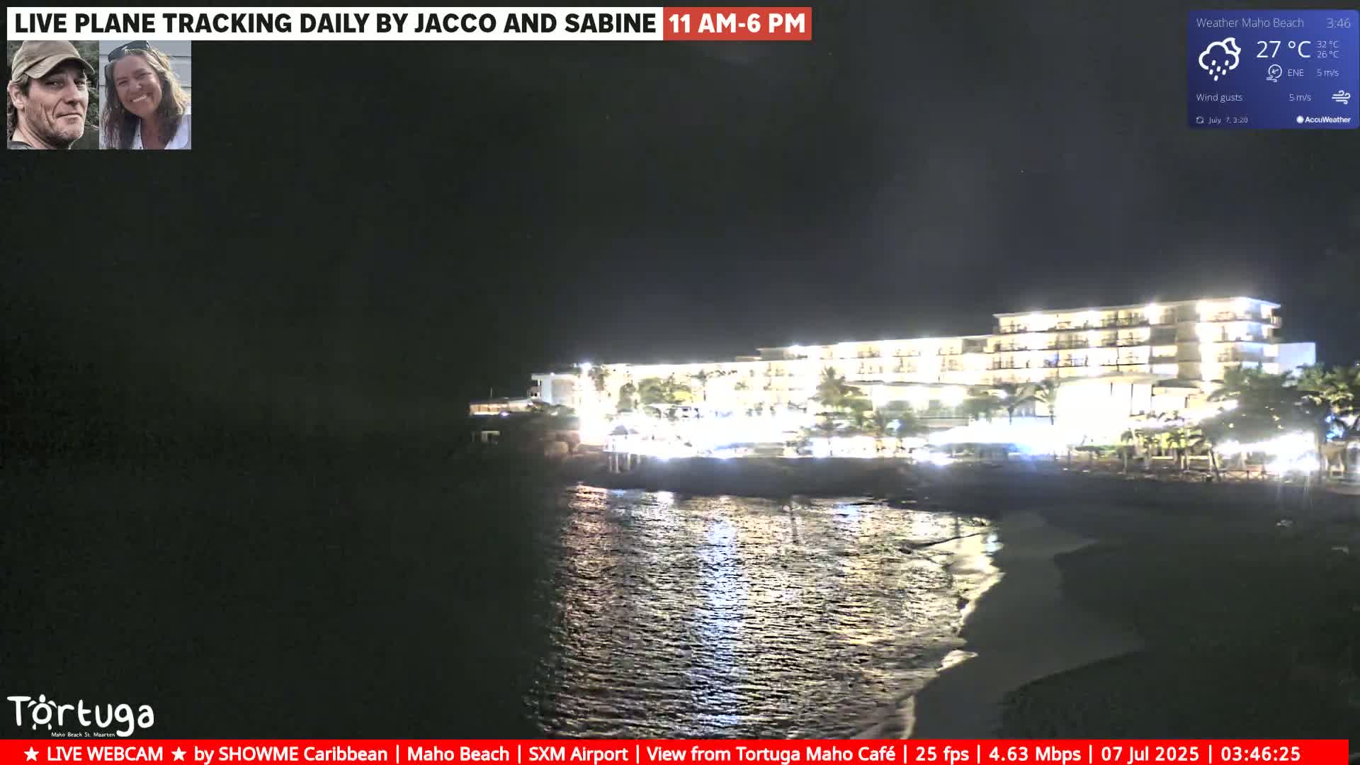 A brightly lit hotel is seen at night next to a dark body of water under slightly cloudy skies with a light breeze.