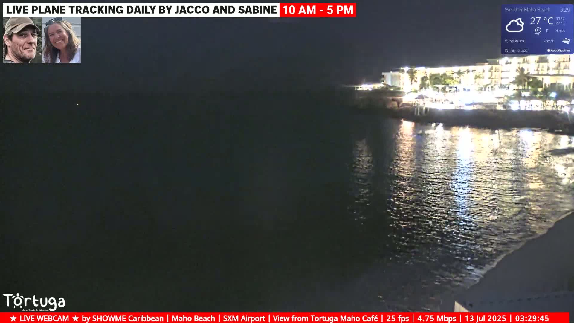 A nighttime view of a calm body of water next to a brightly lit resort under cloudy skies.