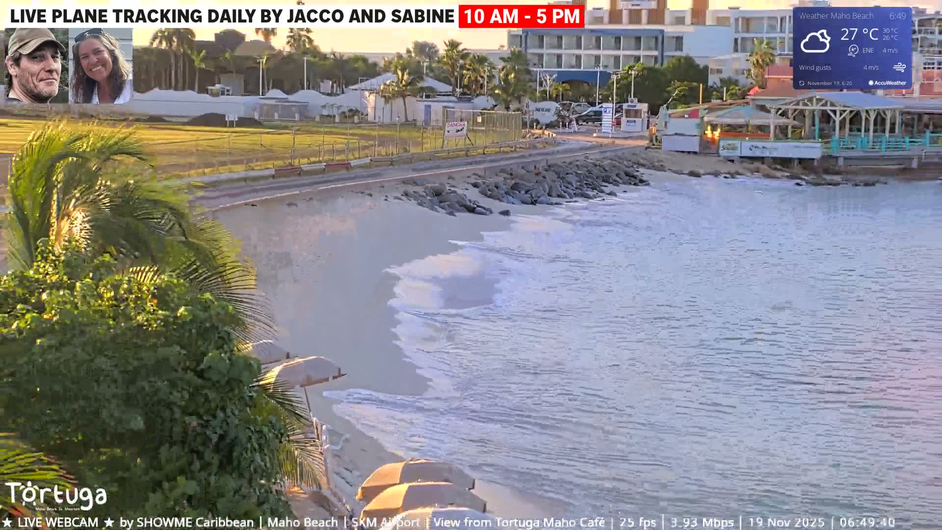 A nighttime view of an airport runway and surrounding buildings under a dark, cloudy sky with a slight wind.