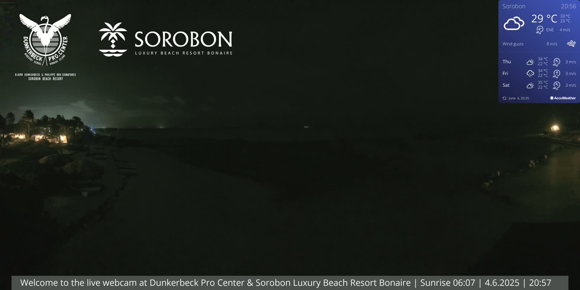 A nighttime, low-light view of a dark beach and ocean under a cloudy sky with a slight wind.