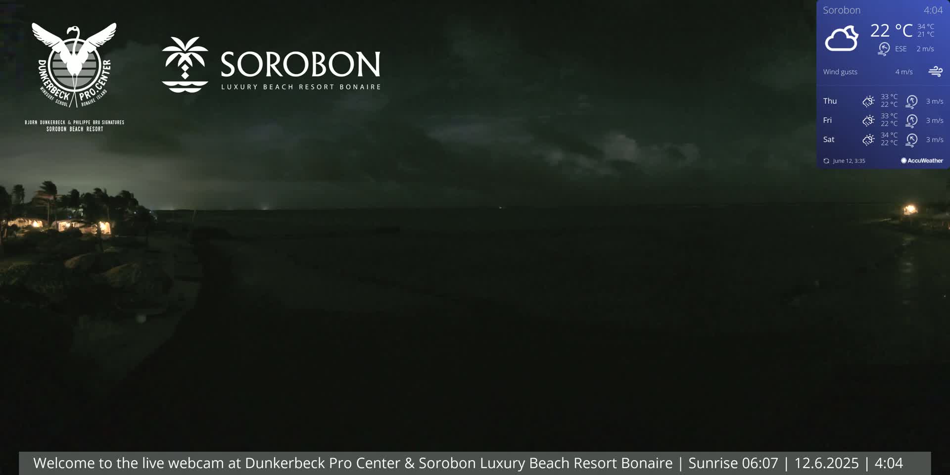 A nighttime coastal scene shows a dark ocean under a cloudy sky, with a few lights visible on the shore.