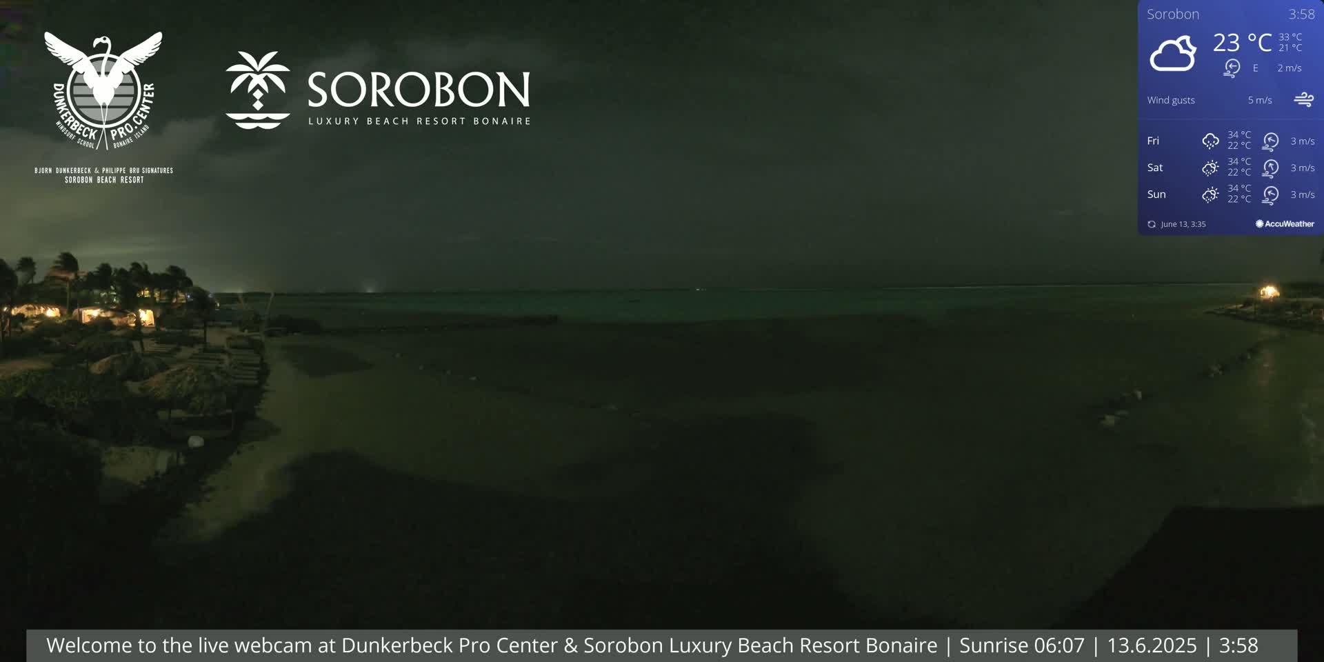 A nighttime beach scene with calm water under a cloudy sky and a gentle breeze.