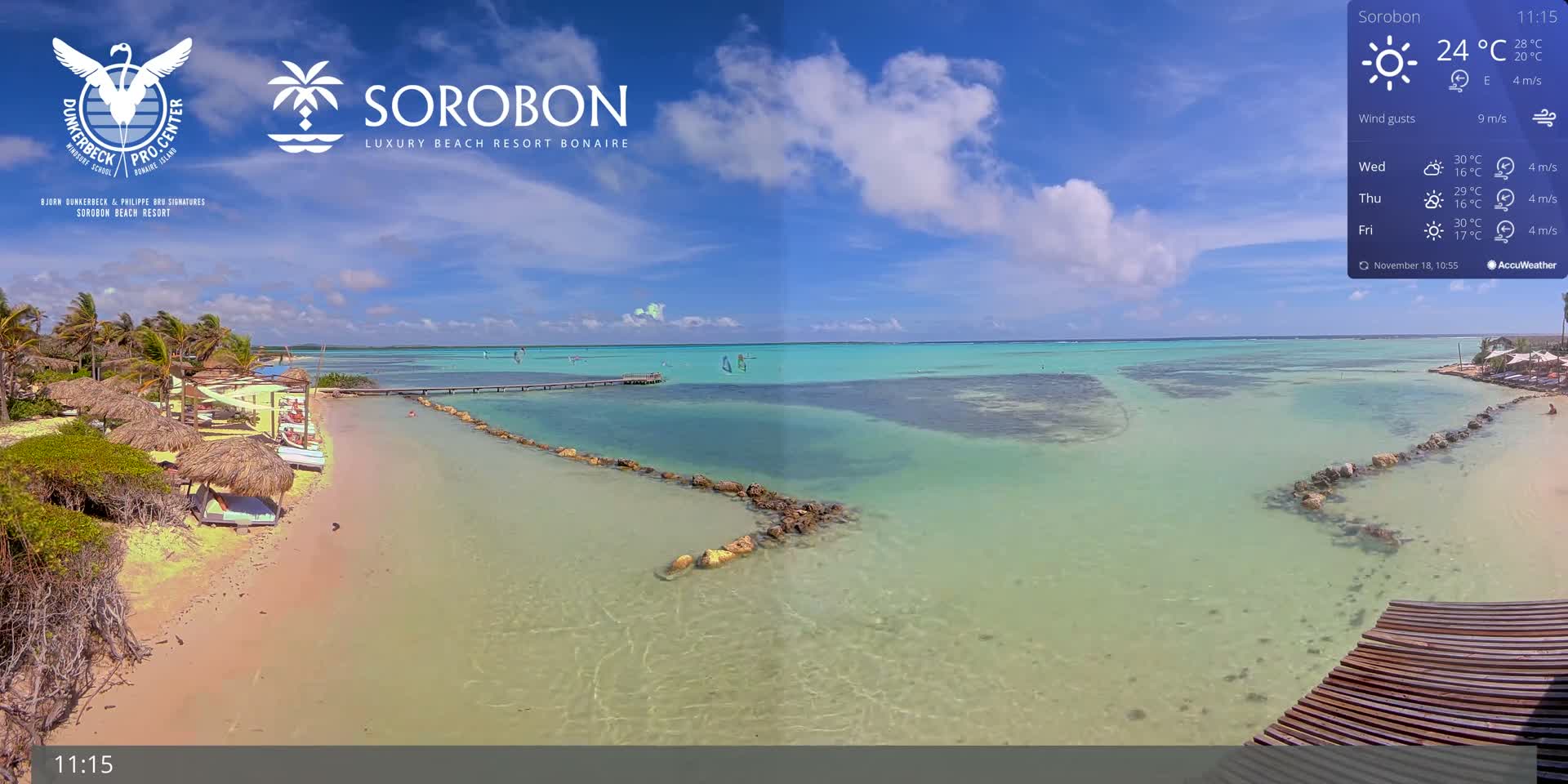A nighttime, dark image shows a dimly lit shoreline with a few lights visible, under a cloudy sky with a slight wind.