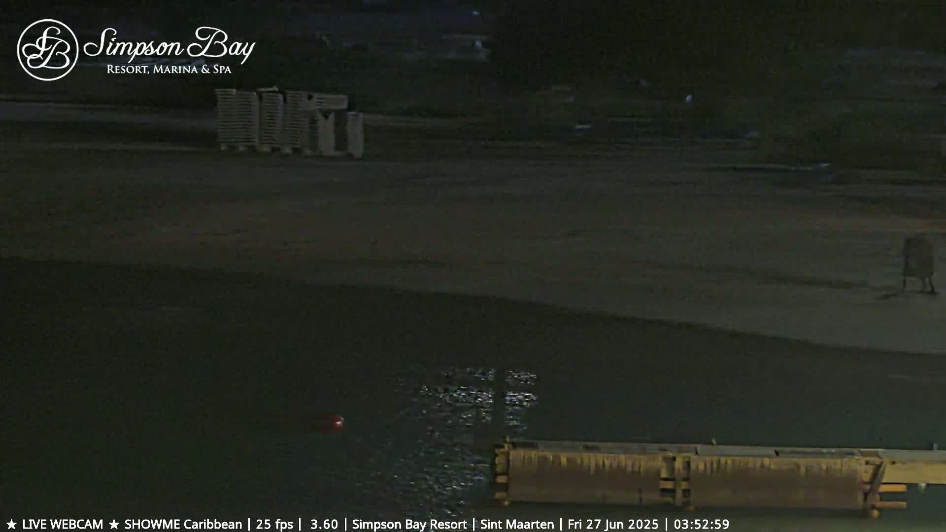 A dark, nighttime beach scene shows a body of water with a dock, and a lone person walking on the sand.