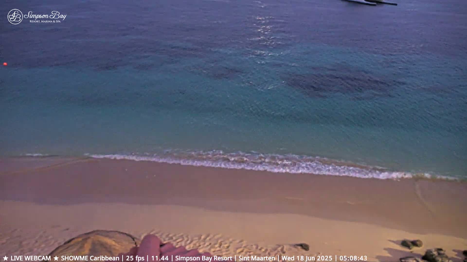 A sandy beach meets calm, turquoise ocean under an evening sky.