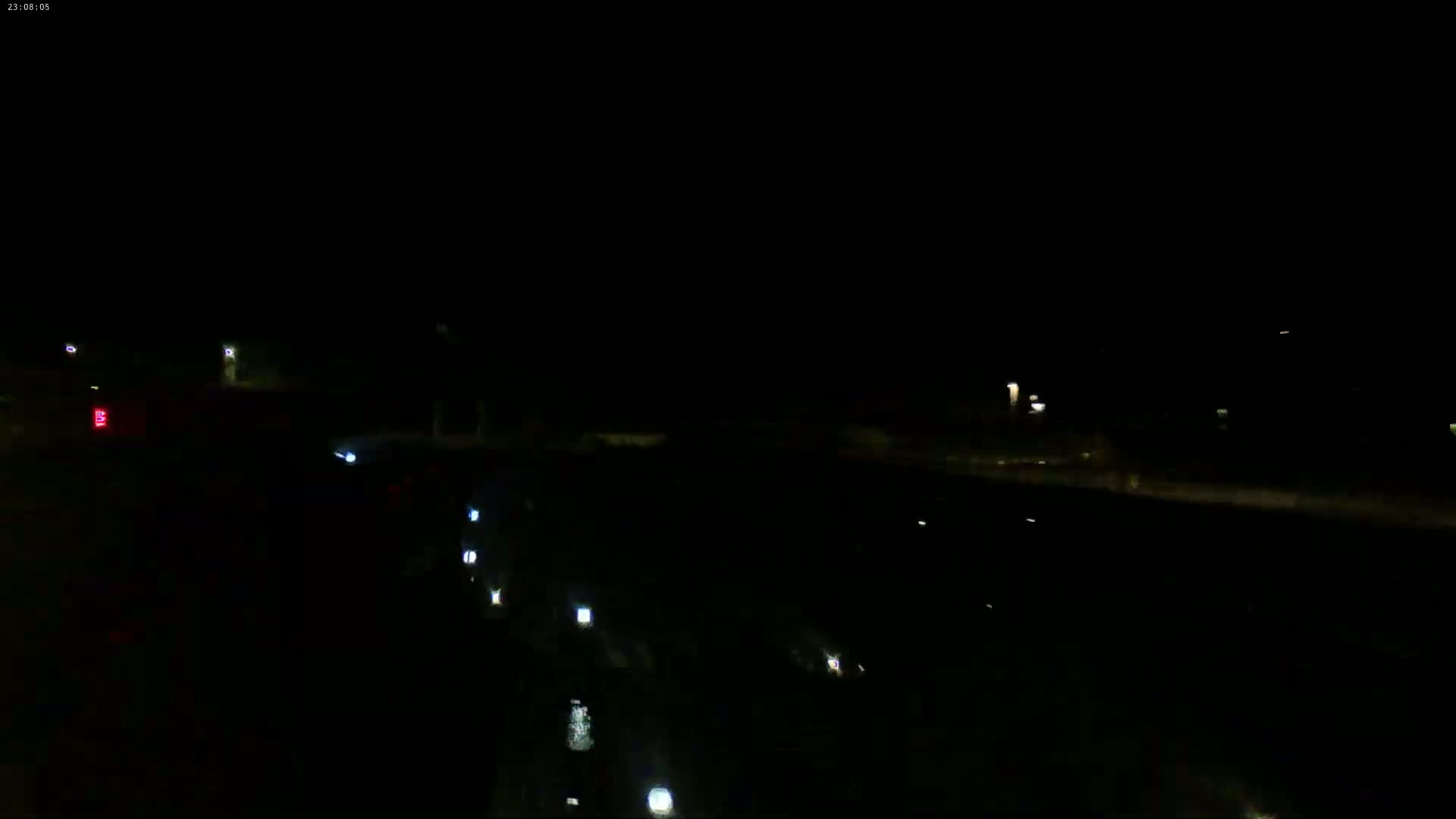 At night, several pairs of vehicle headlights are visible on a dark road.
