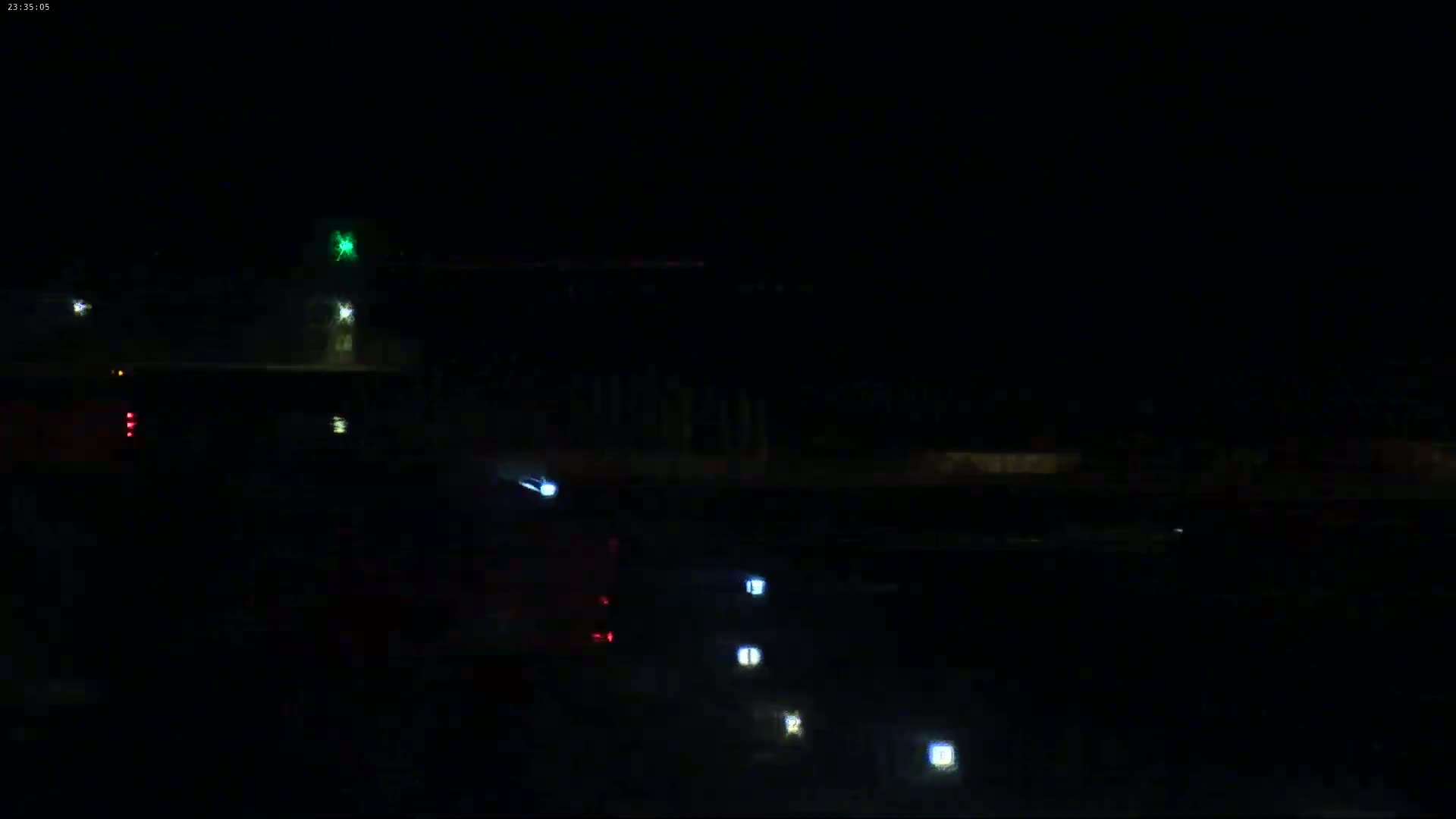 A nighttime, dark scene shows a road with a few vehicles and illuminated road markers.