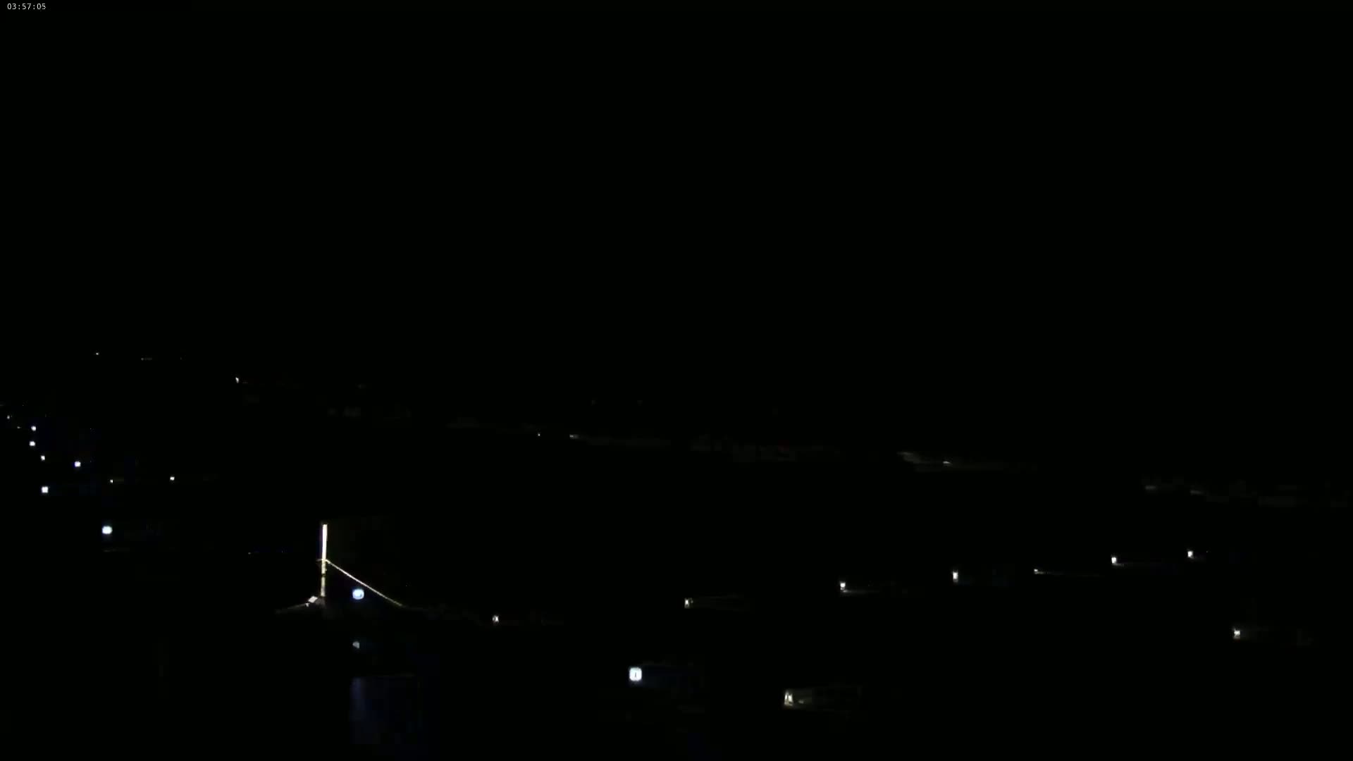 At night, a long line of small lights stretches across a dark, seemingly empty expanse.