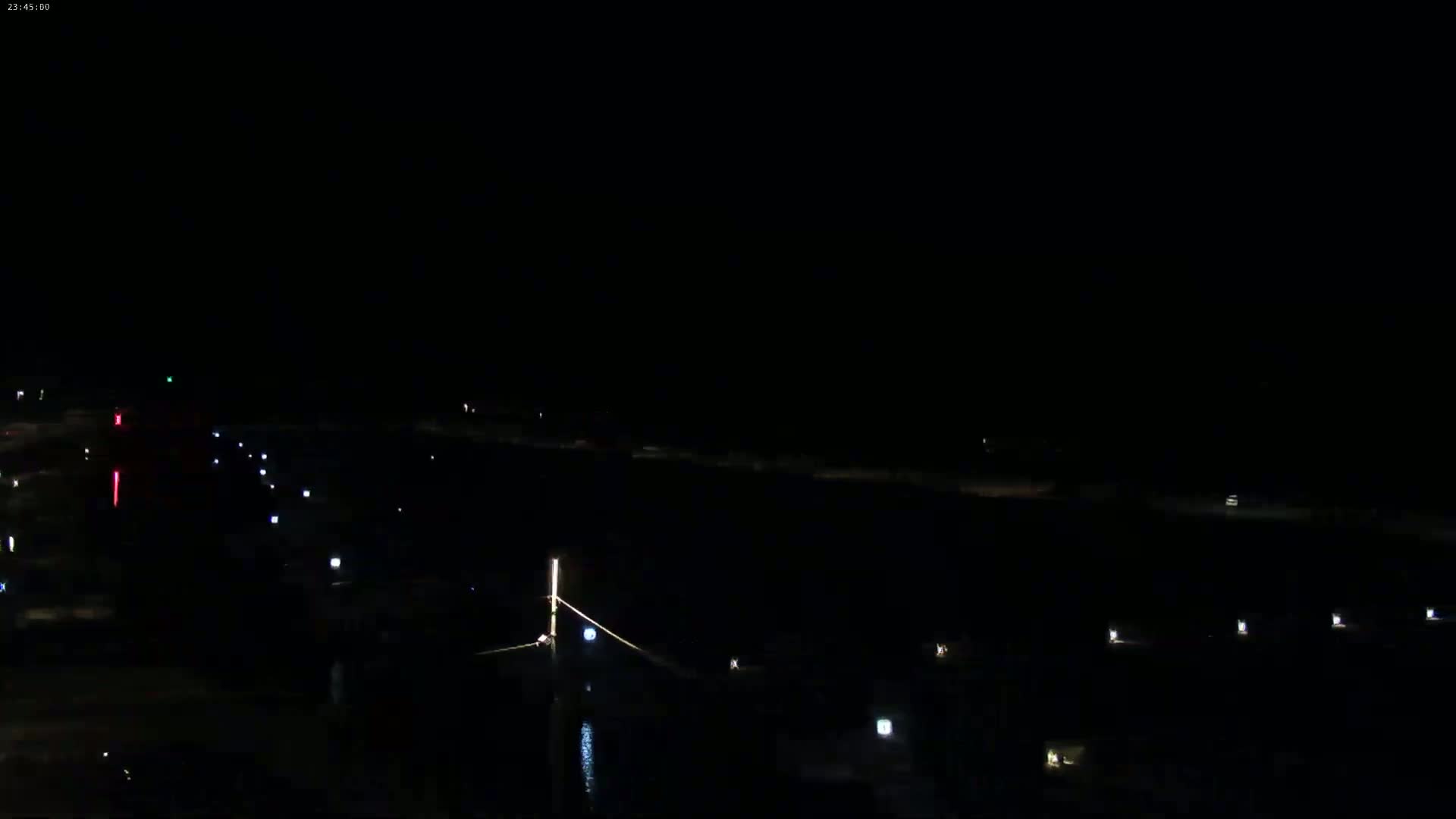 A nighttime long shot shows a dark body of water with a few scattered lights along its edges.