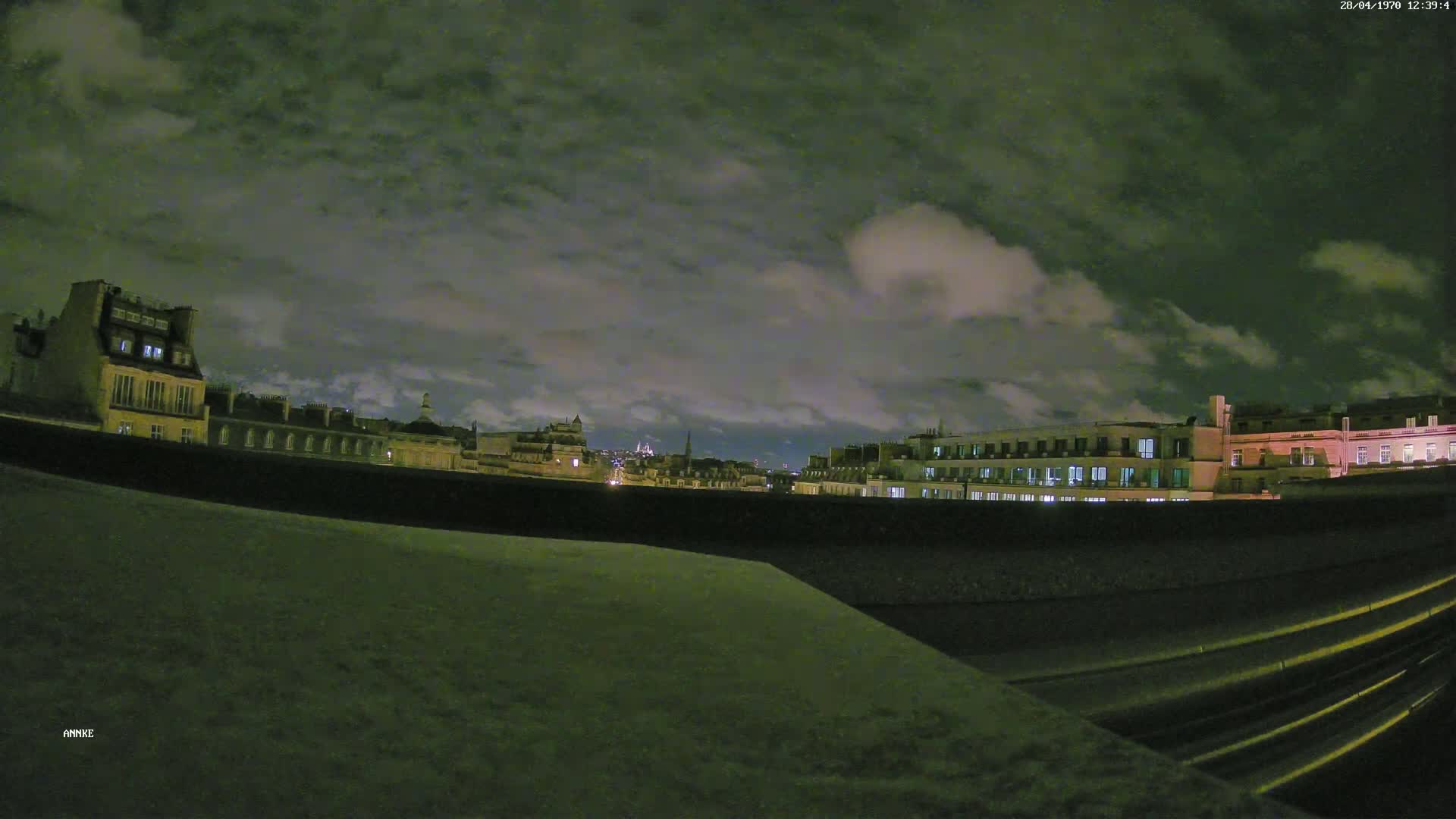 A nighttime view of city buildings under a cloudy sky.