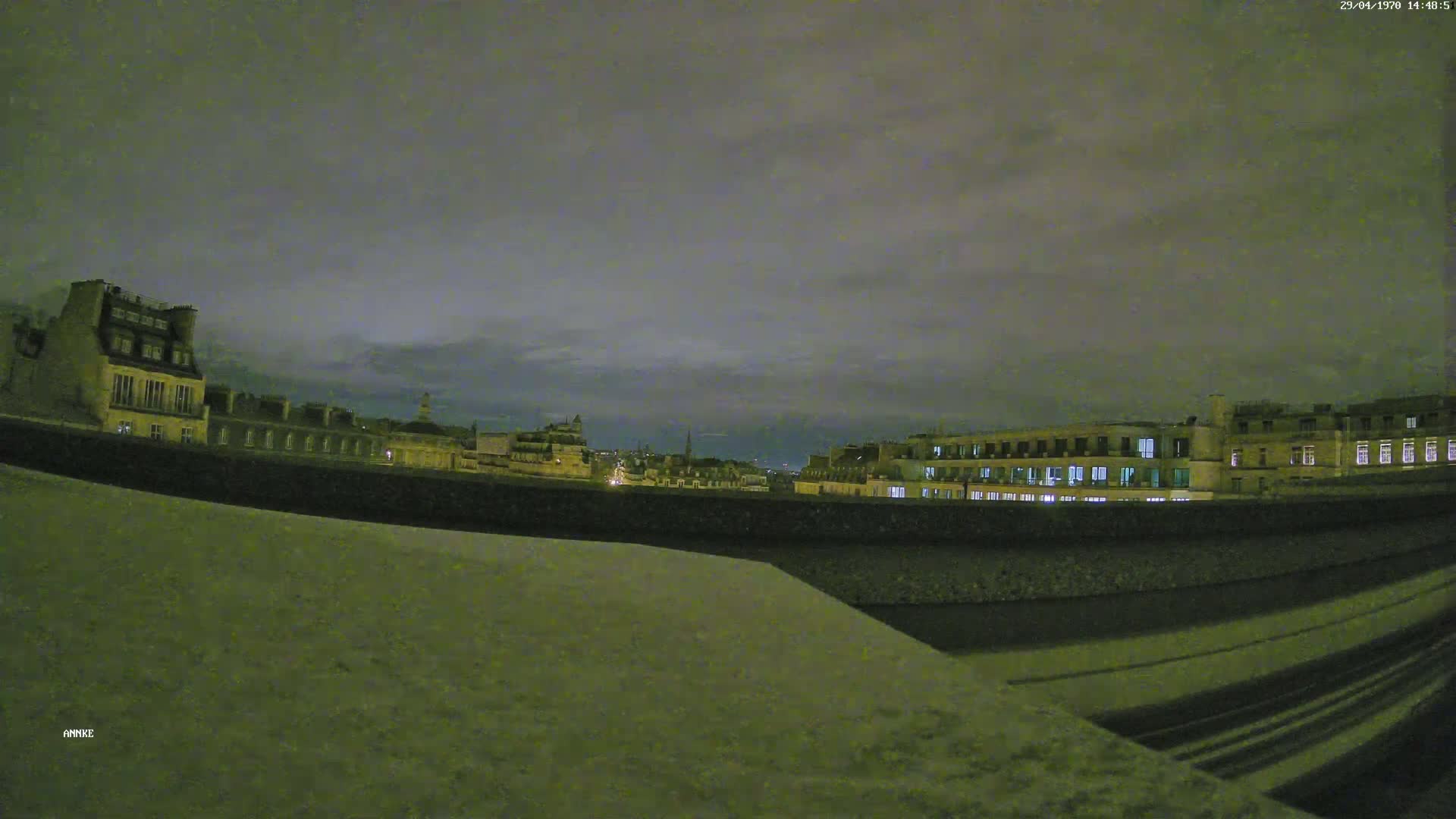 A nighttime view of city buildings under a cloudy sky.