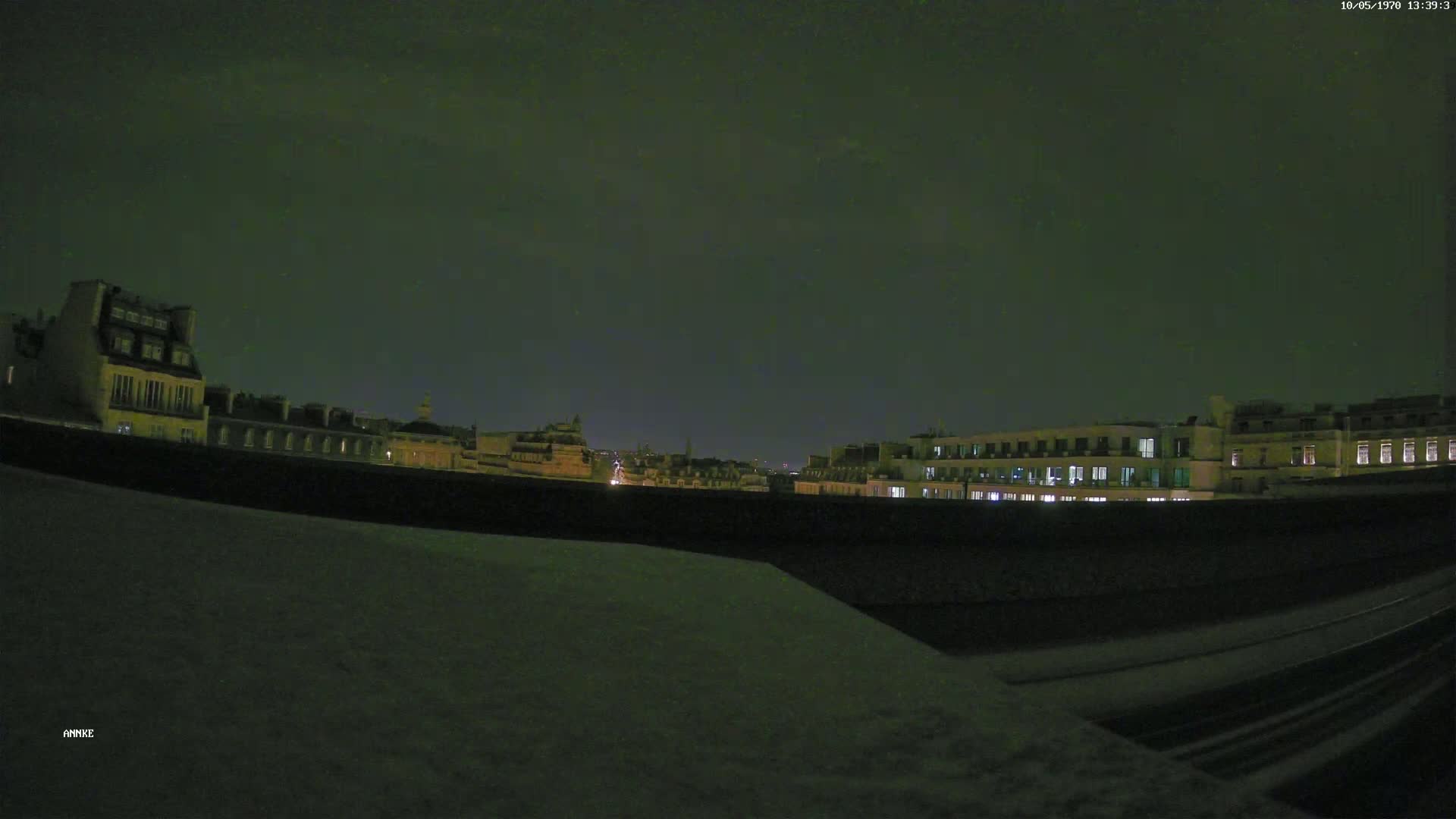 A nighttime view of city buildings with some lights on, under a dark, cloudy sky.