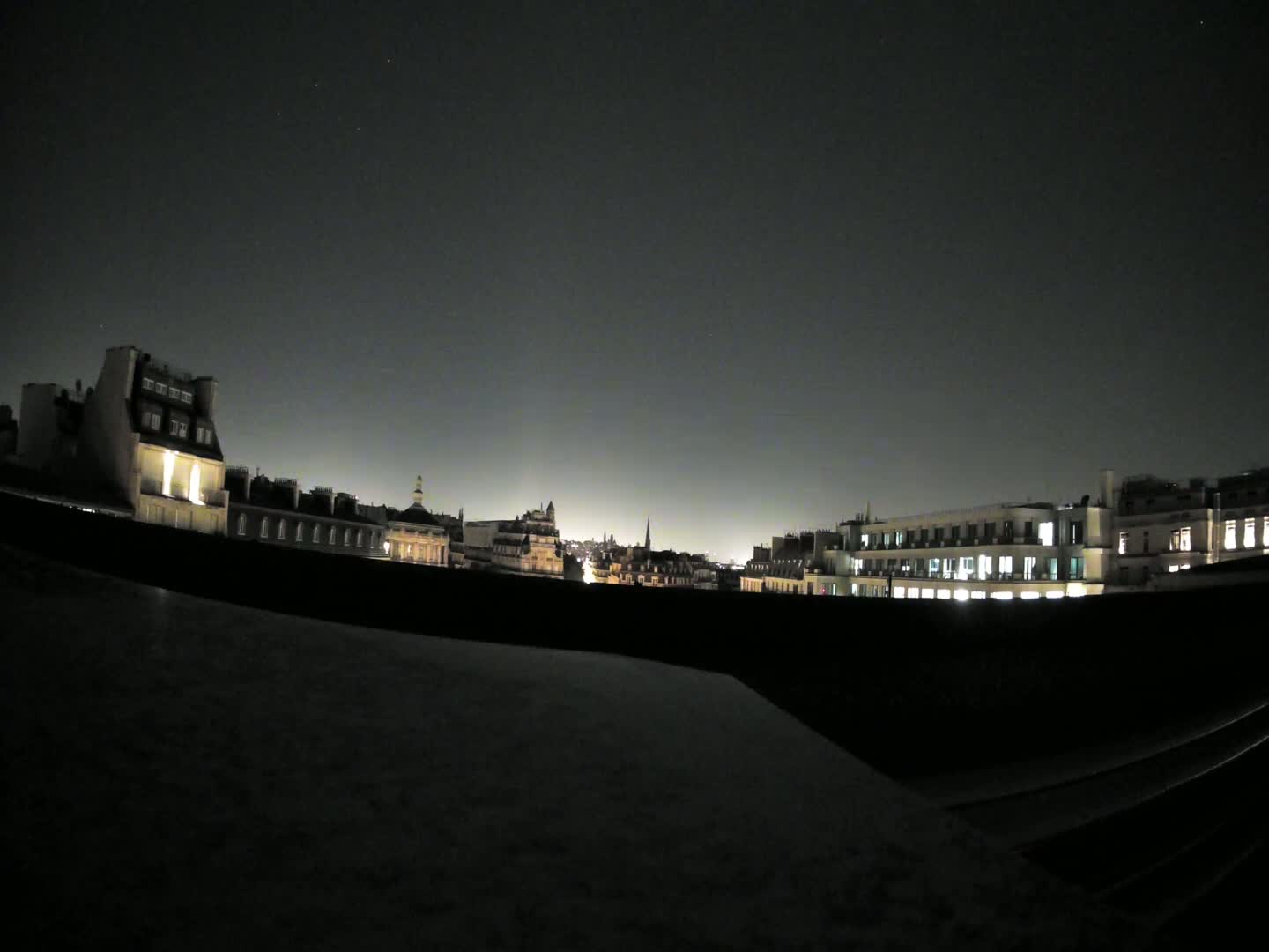 A nighttime view of a city skyline, showing illuminated buildings under a dark, clear sky.