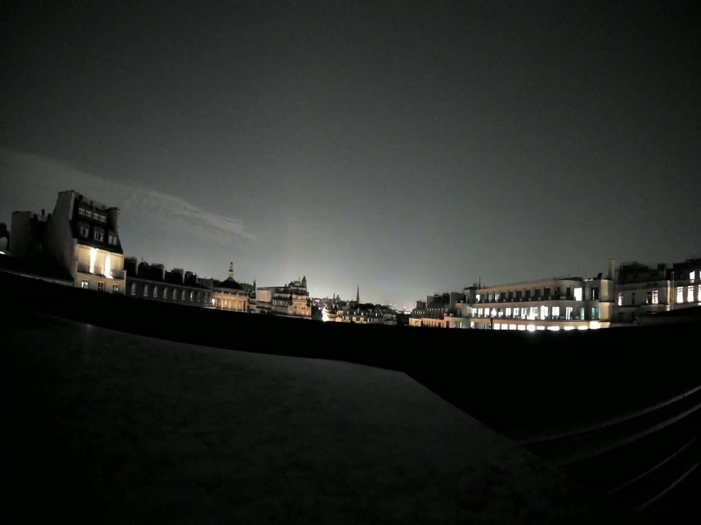 A nighttime cityscape of illuminated buildings under a dark, mostly clear sky.