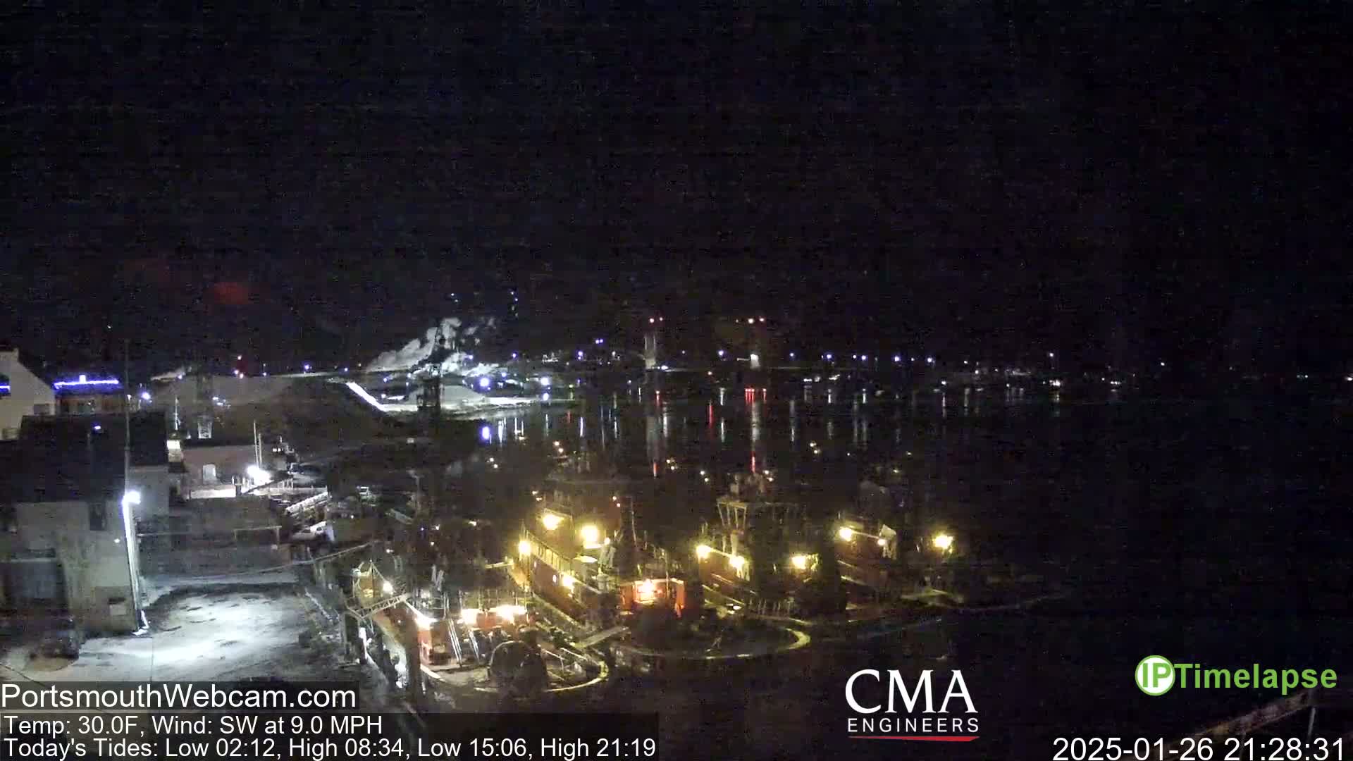 A nighttime, low-temperature view of several tugboats docked at a harbor under a clear, dark sky with a southwest wind.