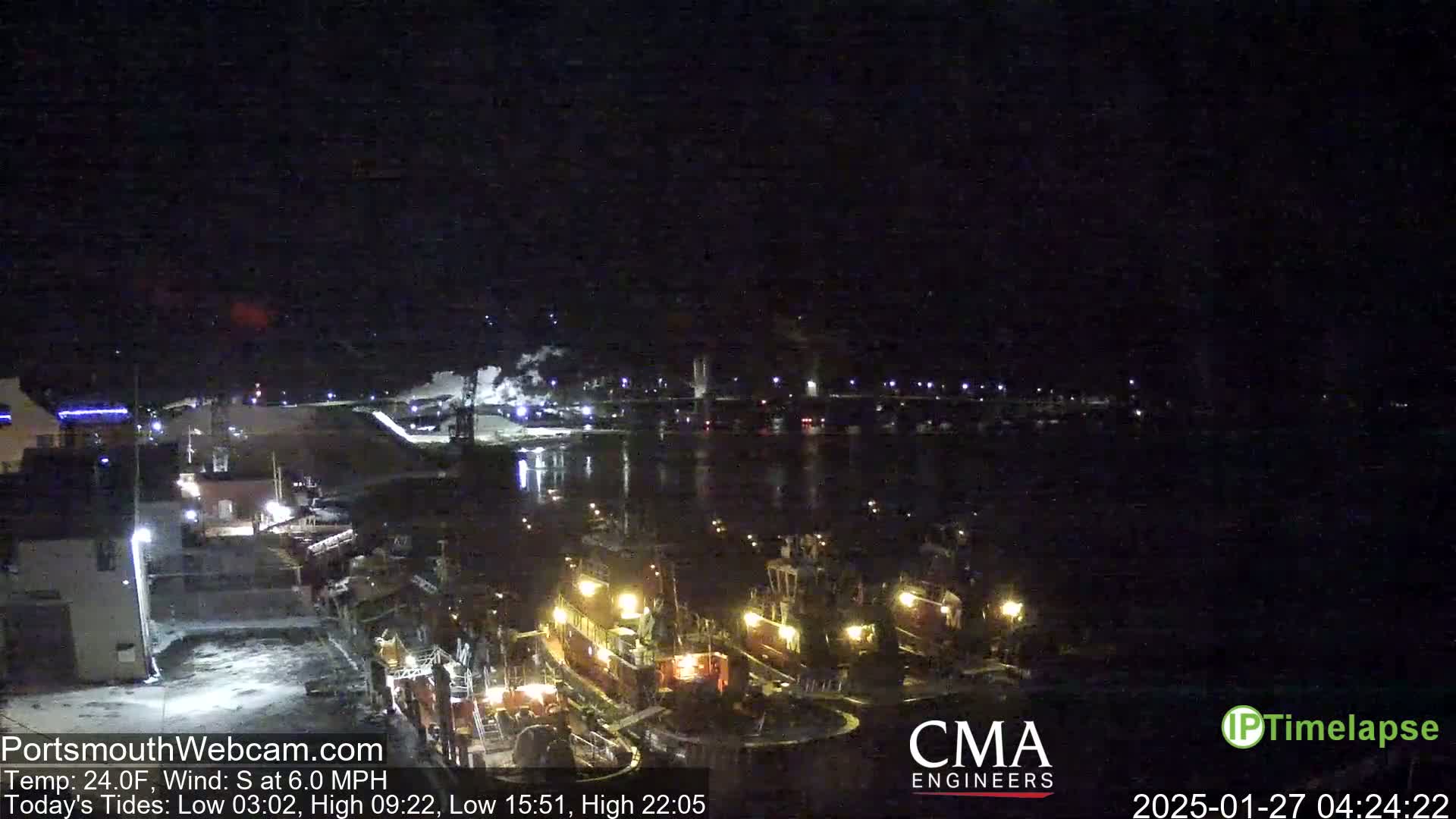 At night, under a clear sky with a south wind of 6 mph and a temperature of 24°F, several boats are docked at a waterfront, with lights illuminating the scene.