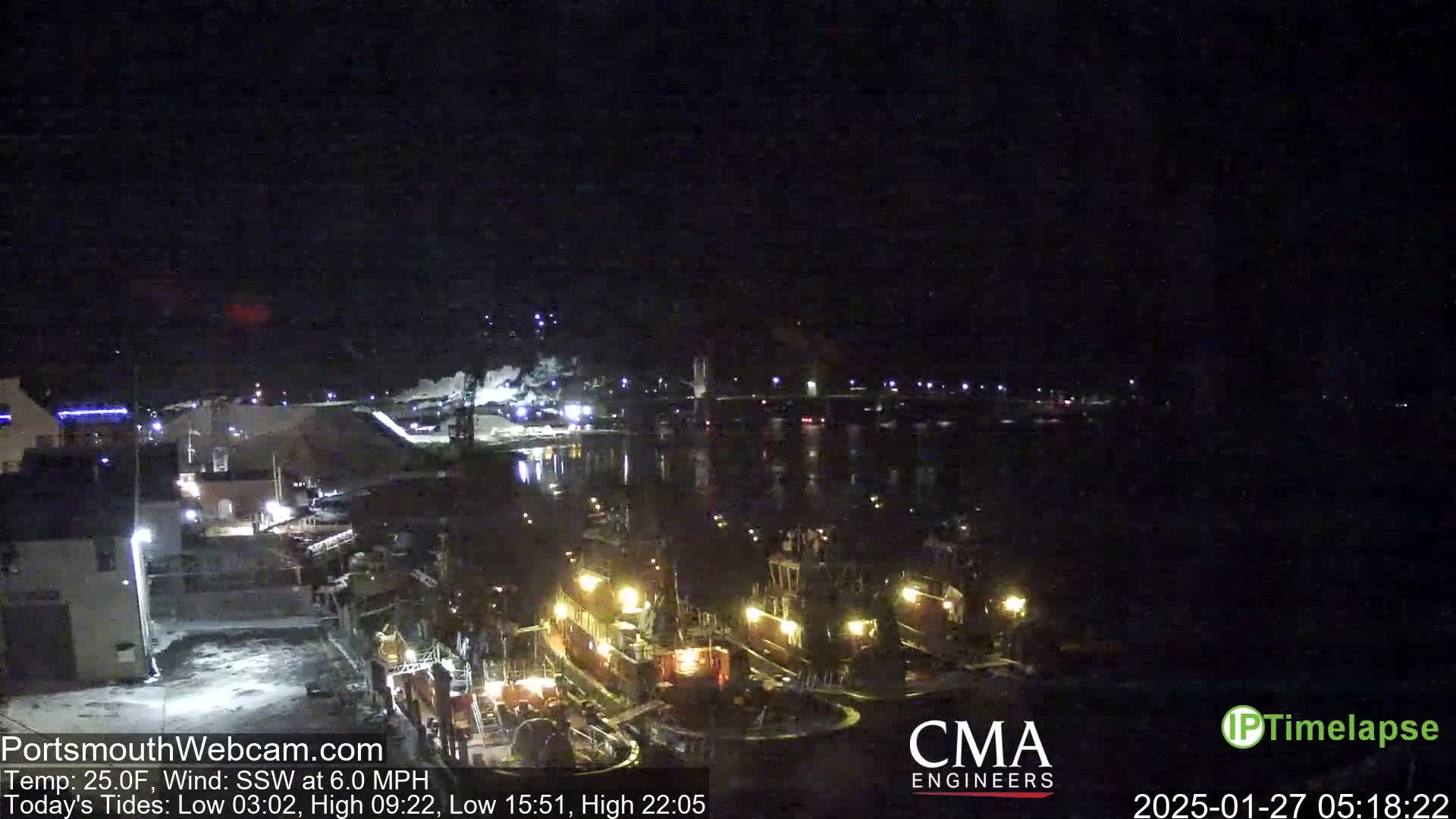 A nighttime view of a harbor with several docked tugboats, under a dark, clear sky and a 25°F temperature with a southwest wind.