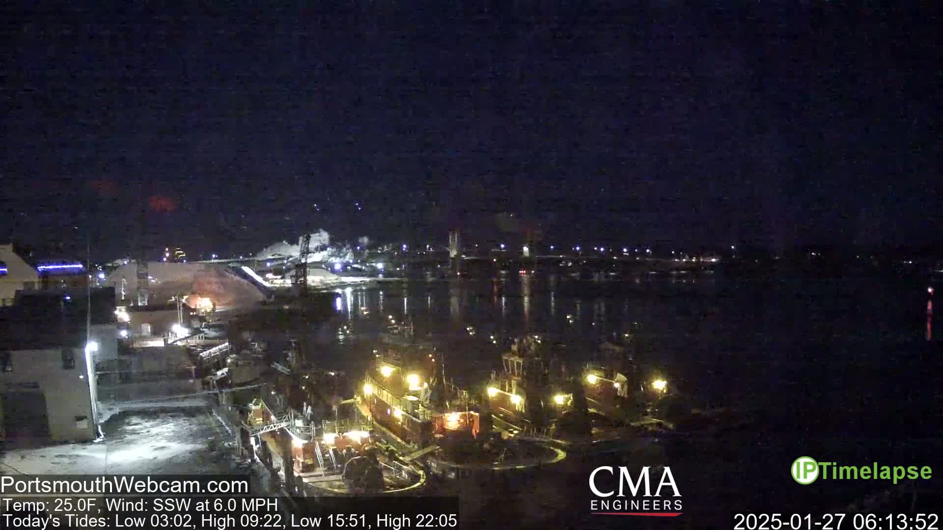 A nighttime view of a harbor with several illuminated tugboats docked, under a clear, dark sky, and a temperature of 25 degrees Fahrenheit.