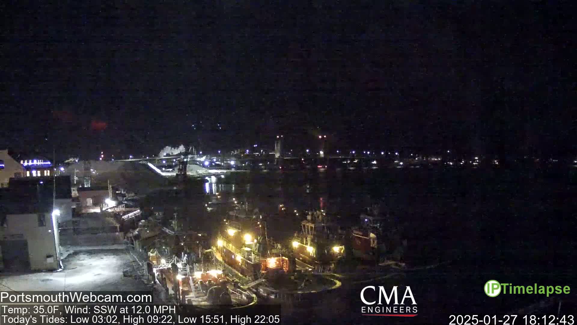 A nighttime harbor scene with several tugboats docked, under a dark sky with a south-southwesterly wind.