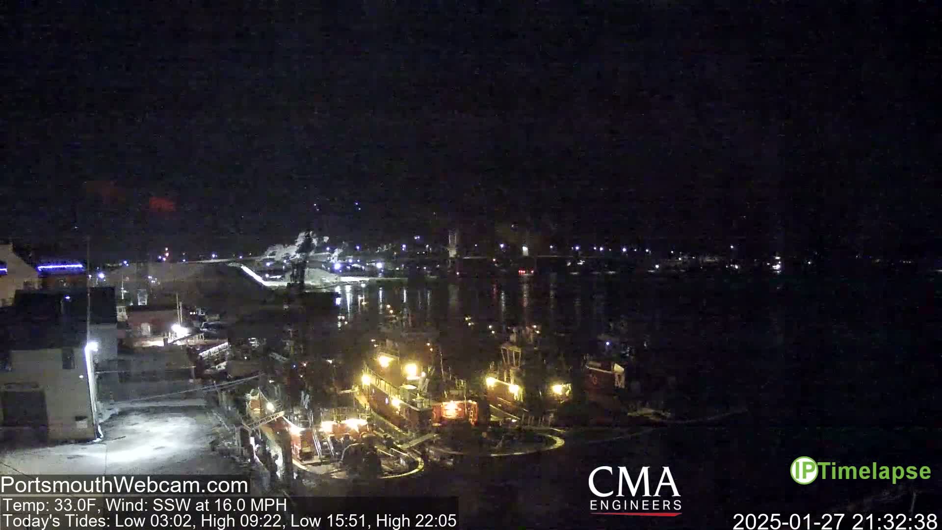 Several tugboats are docked at a nighttime harbor under a dark, clear sky.