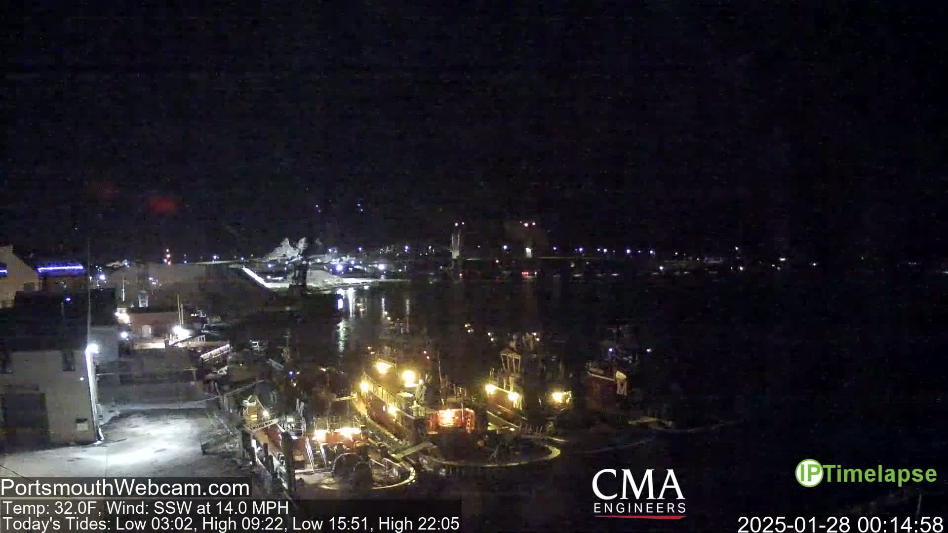 Several tugboats are moored at a dark, nighttime harbor under a clear, dark sky.