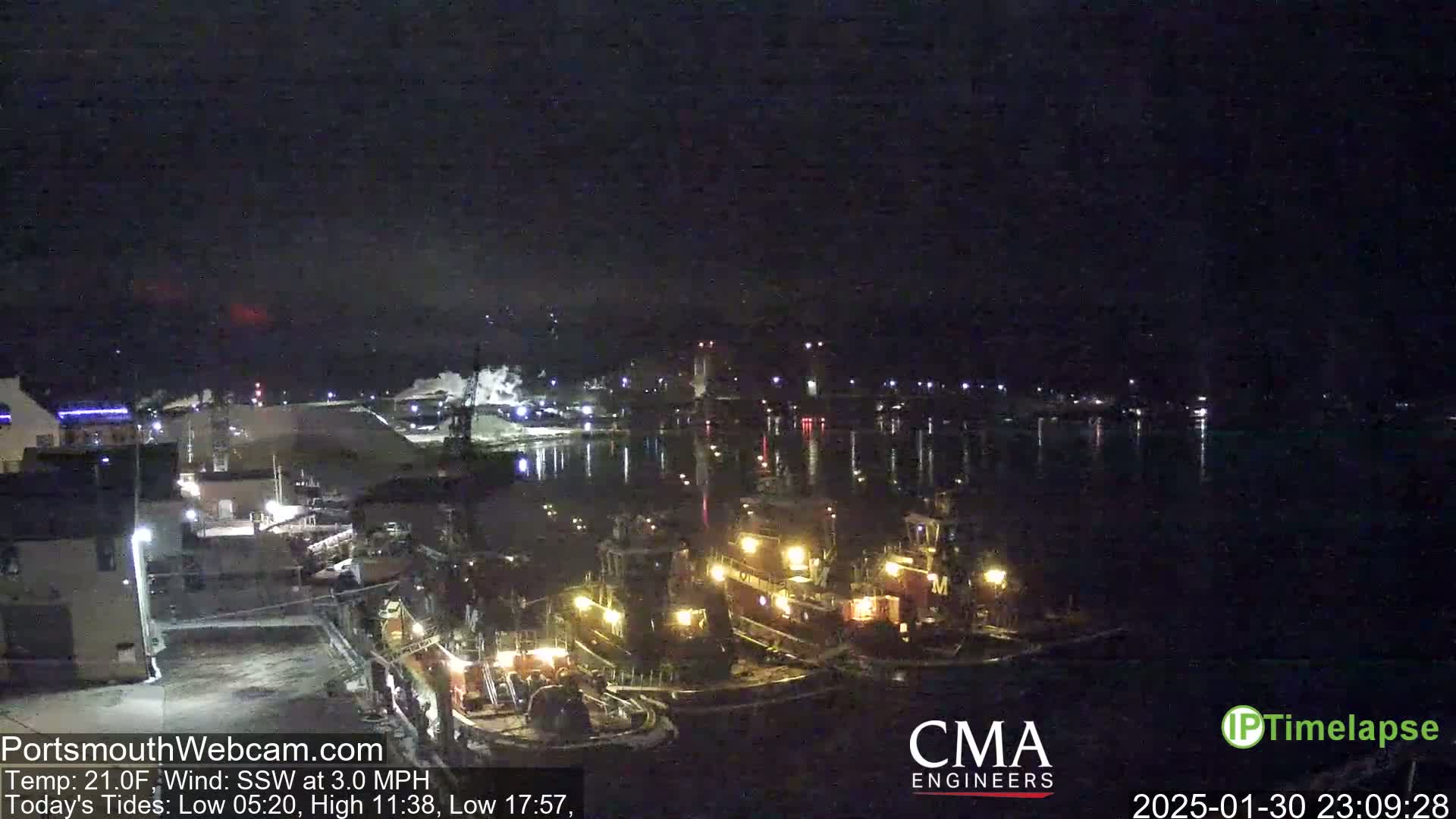 Several tugboats are moored in a dark harbor at night under a clear, cold sky.