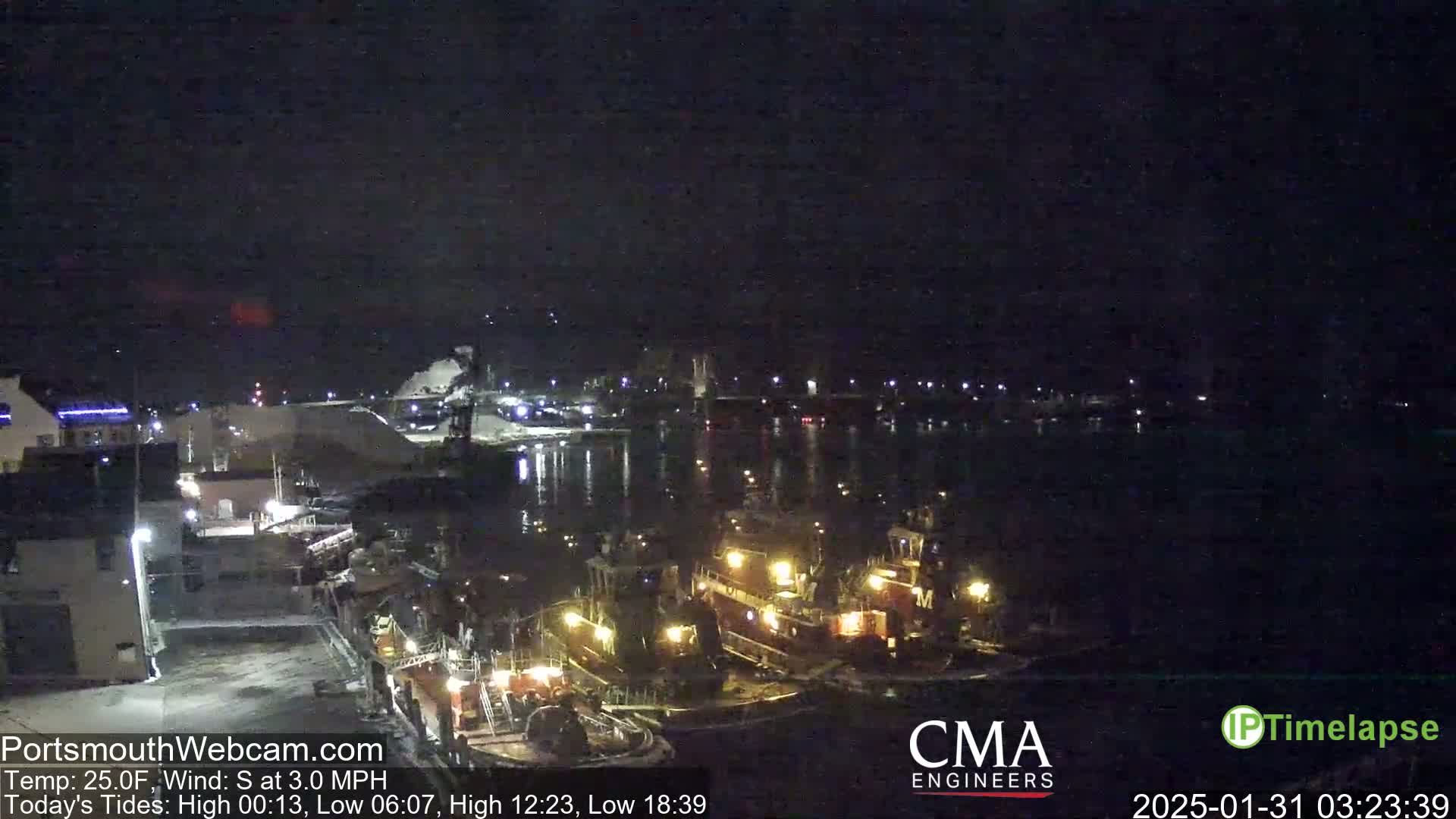 Several tugboats are docked at a nighttime harbor under a dark, clear sky.