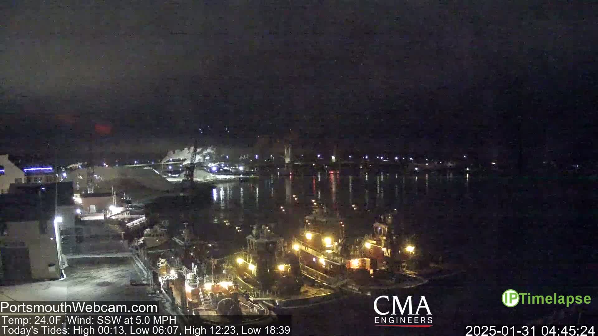 Several tugboats are docked at a harbor at night under a dark, clear sky.