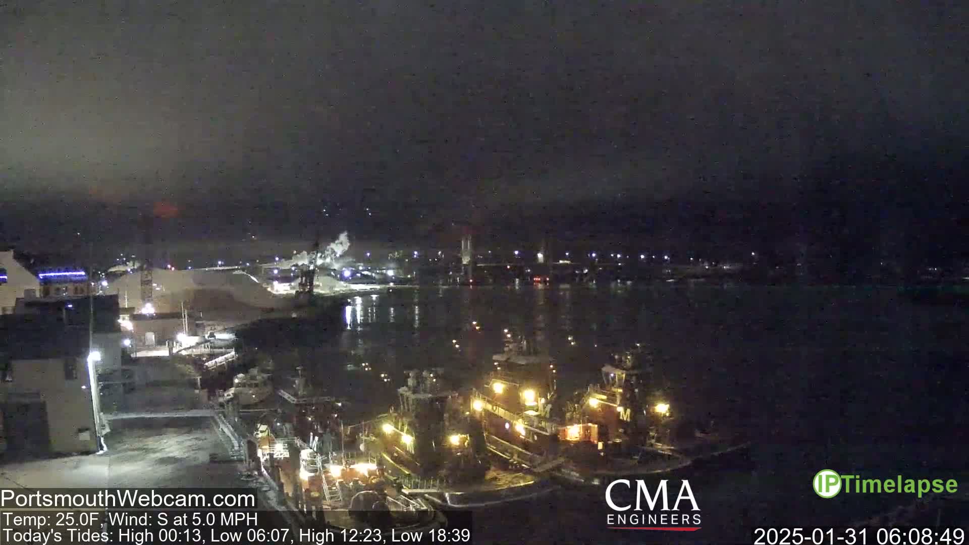 Several tugboats are moored in a dark harbor at night under a mostly clear sky.