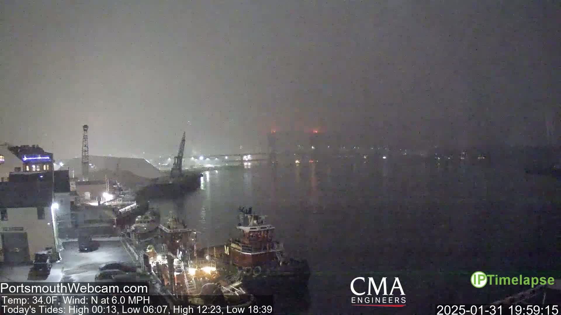A nighttime view of a harbor with tugboats and industrial buildings under foggy conditions.