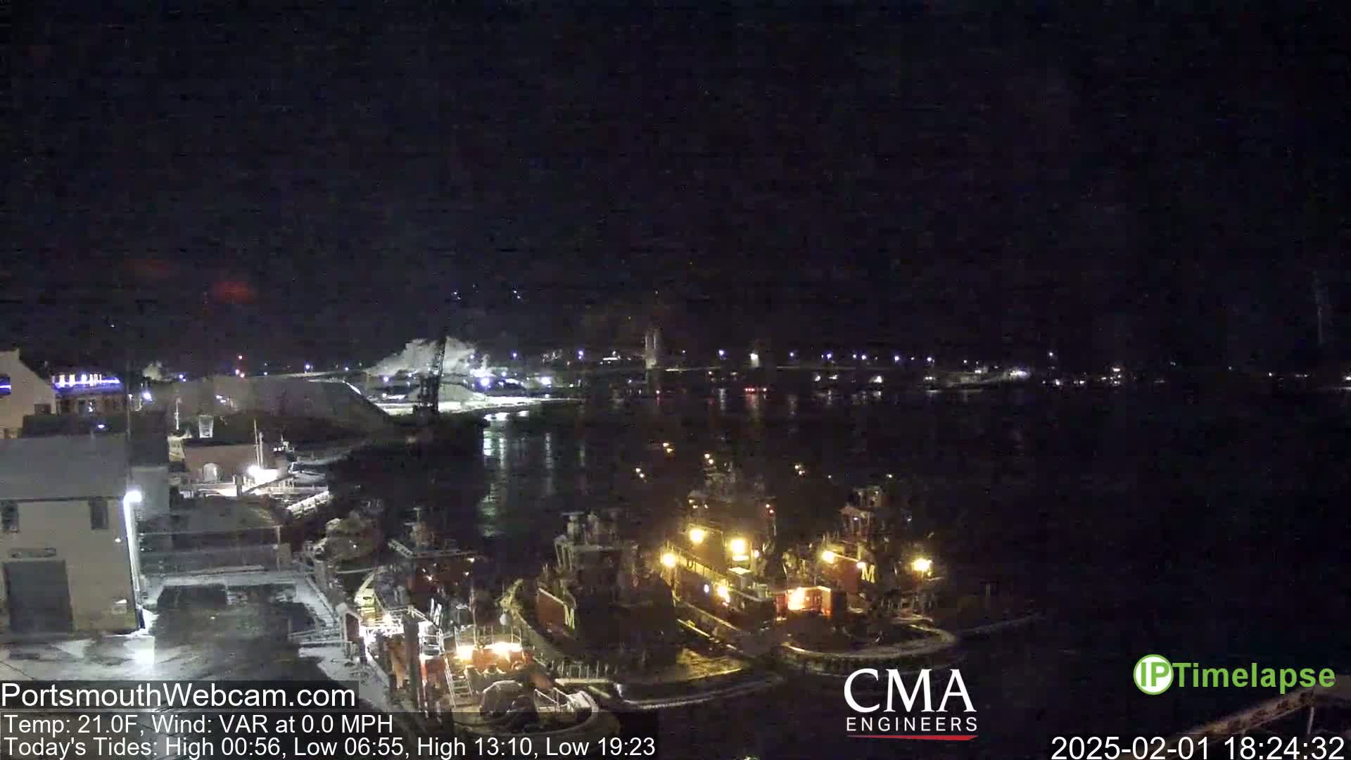 Several tugboats are docked at a nighttime harbor under a dark, clear sky.