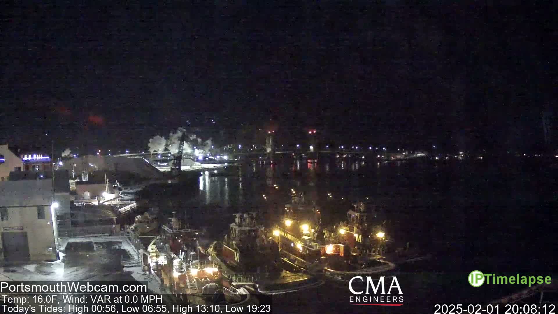 A nighttime view of a harbor with several tugboats docked, under a clear, dark sky.